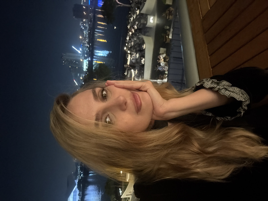 Woman dines at waterfront restaurant overlooking Dubai skyline