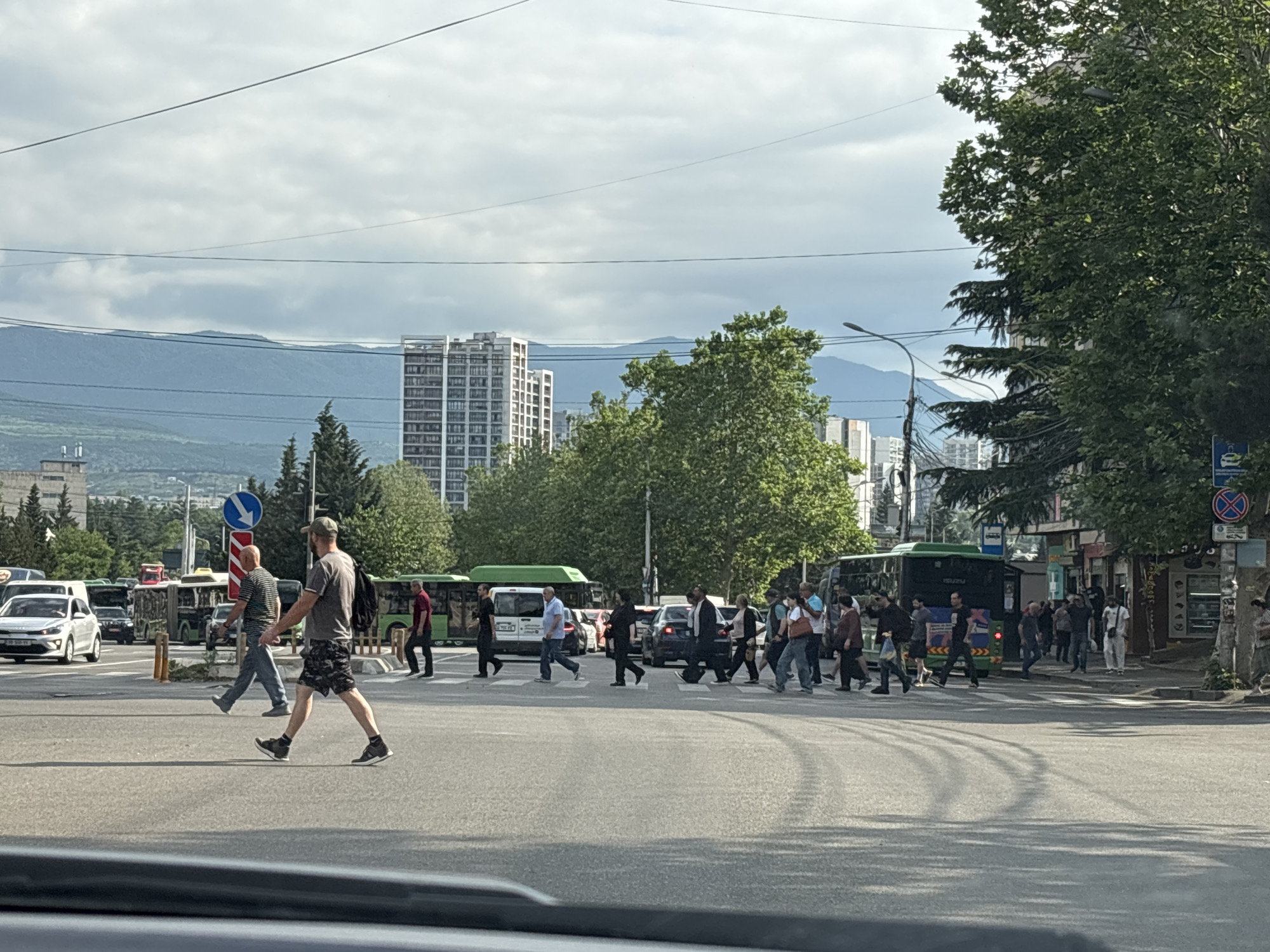 Tbilisi intersection buzzing with traffic and pedestrians on a cloudy morning
