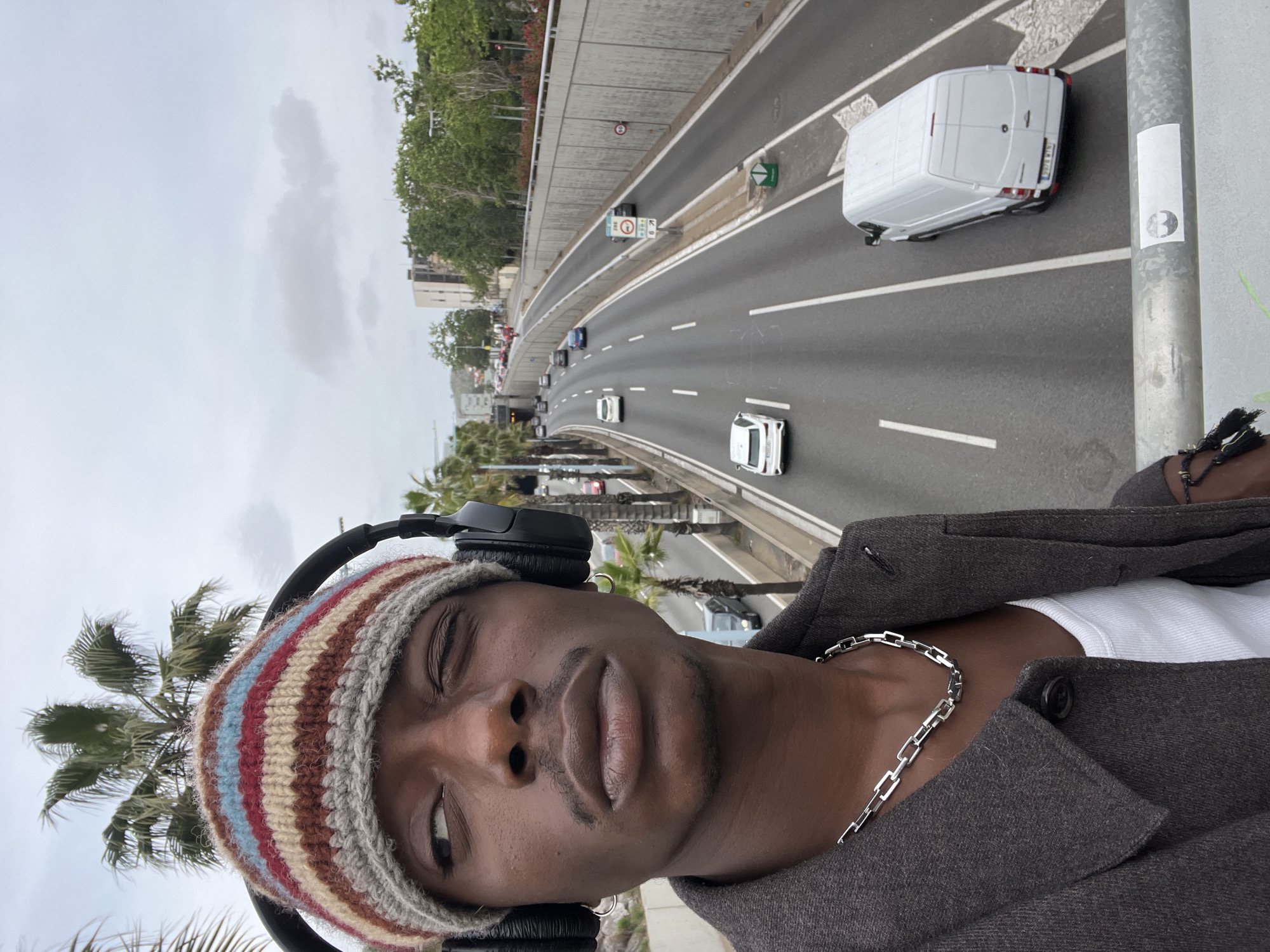 Man takes selfie on Barcelona bridge wearing colorful beanie