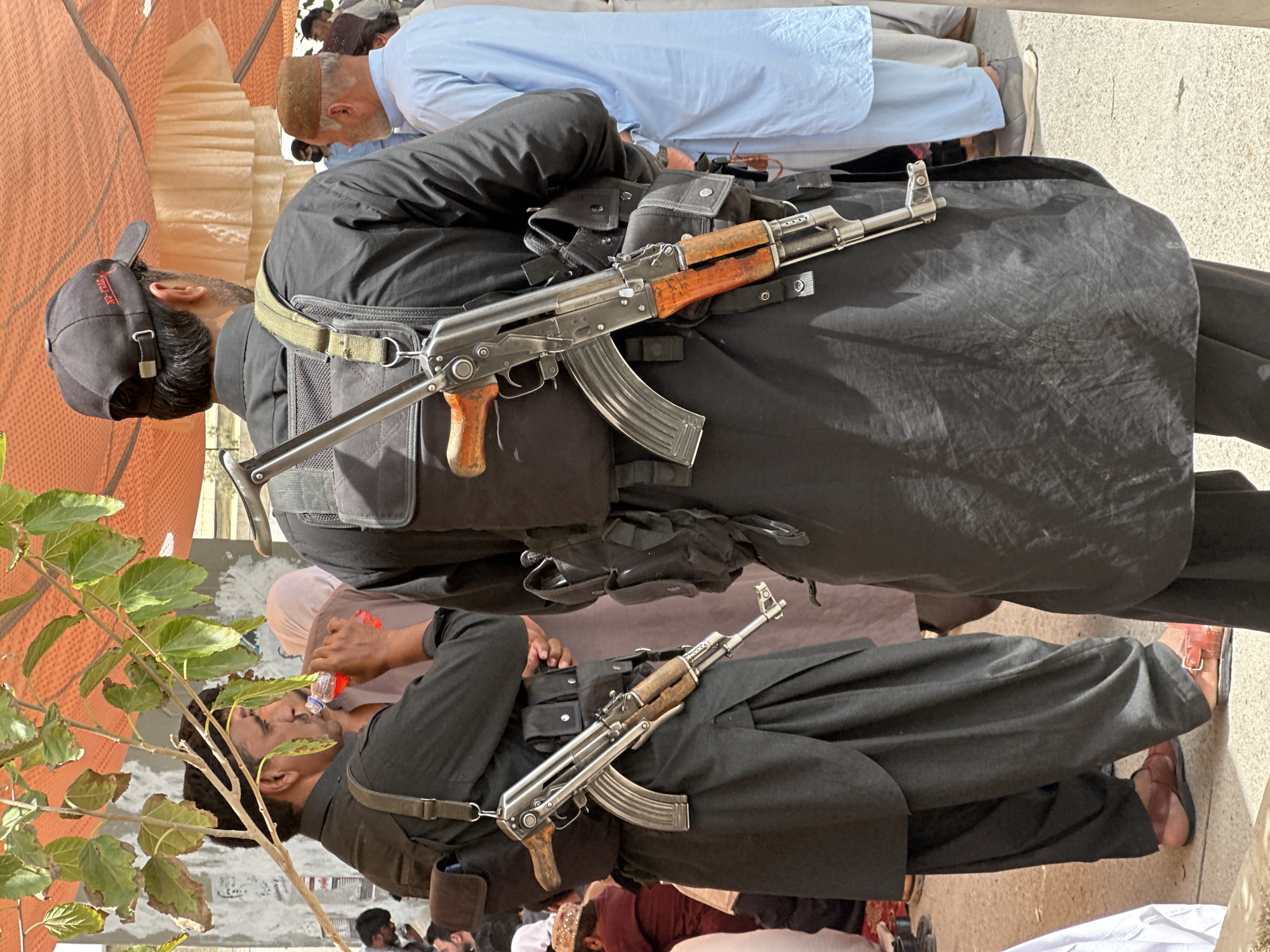 Armed figures and a seated gathering in Quetta, Pakistan