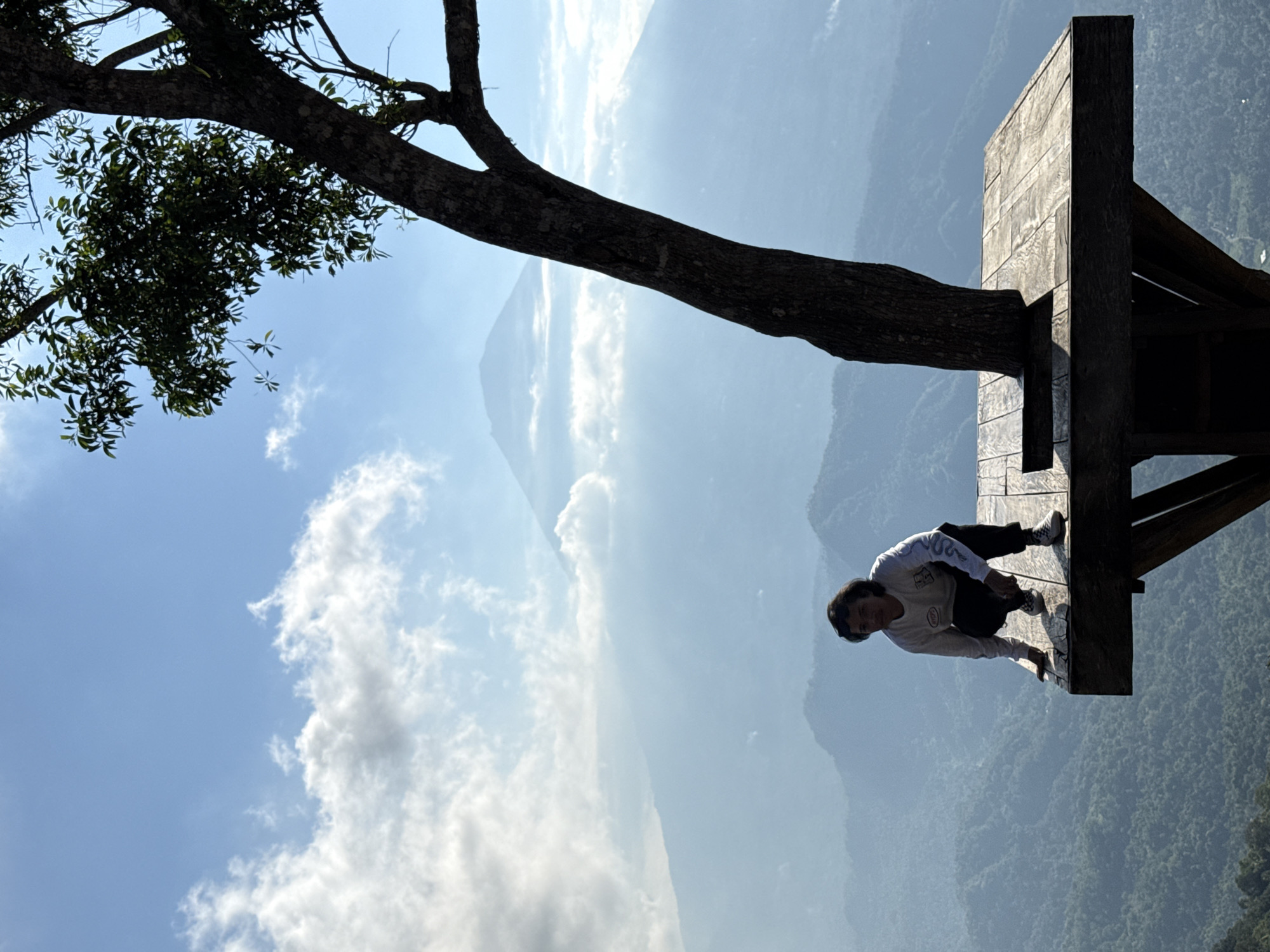 Hilltop platform overlooks misty valley and mountain near Abang