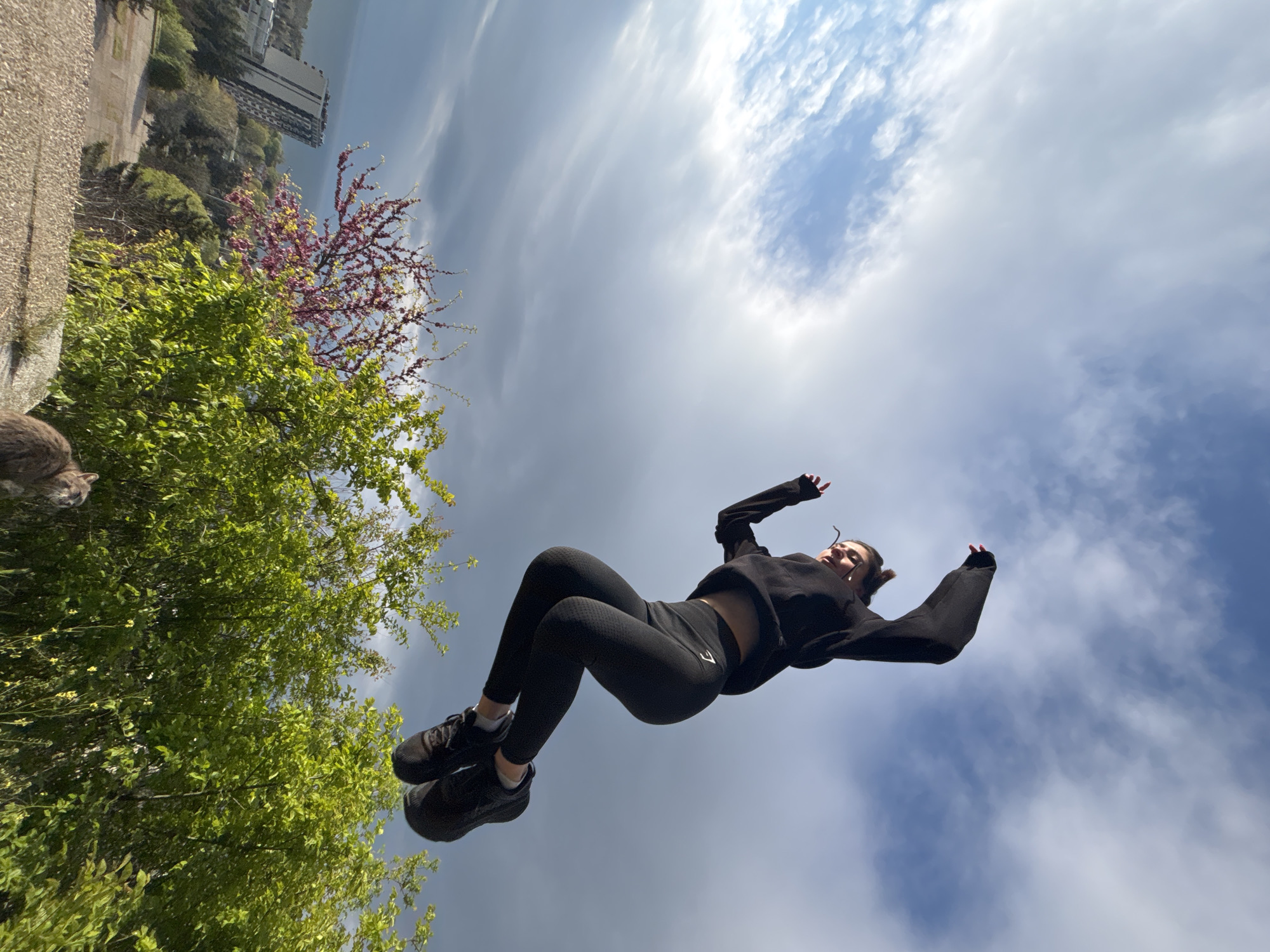 Woman performs athletic jumps, interacts with cat in urban setting
