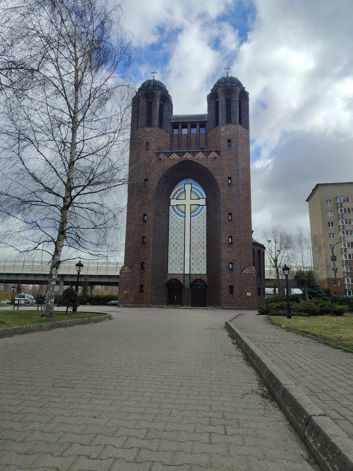 Twin-towered brick church with stained-glass cross window observed