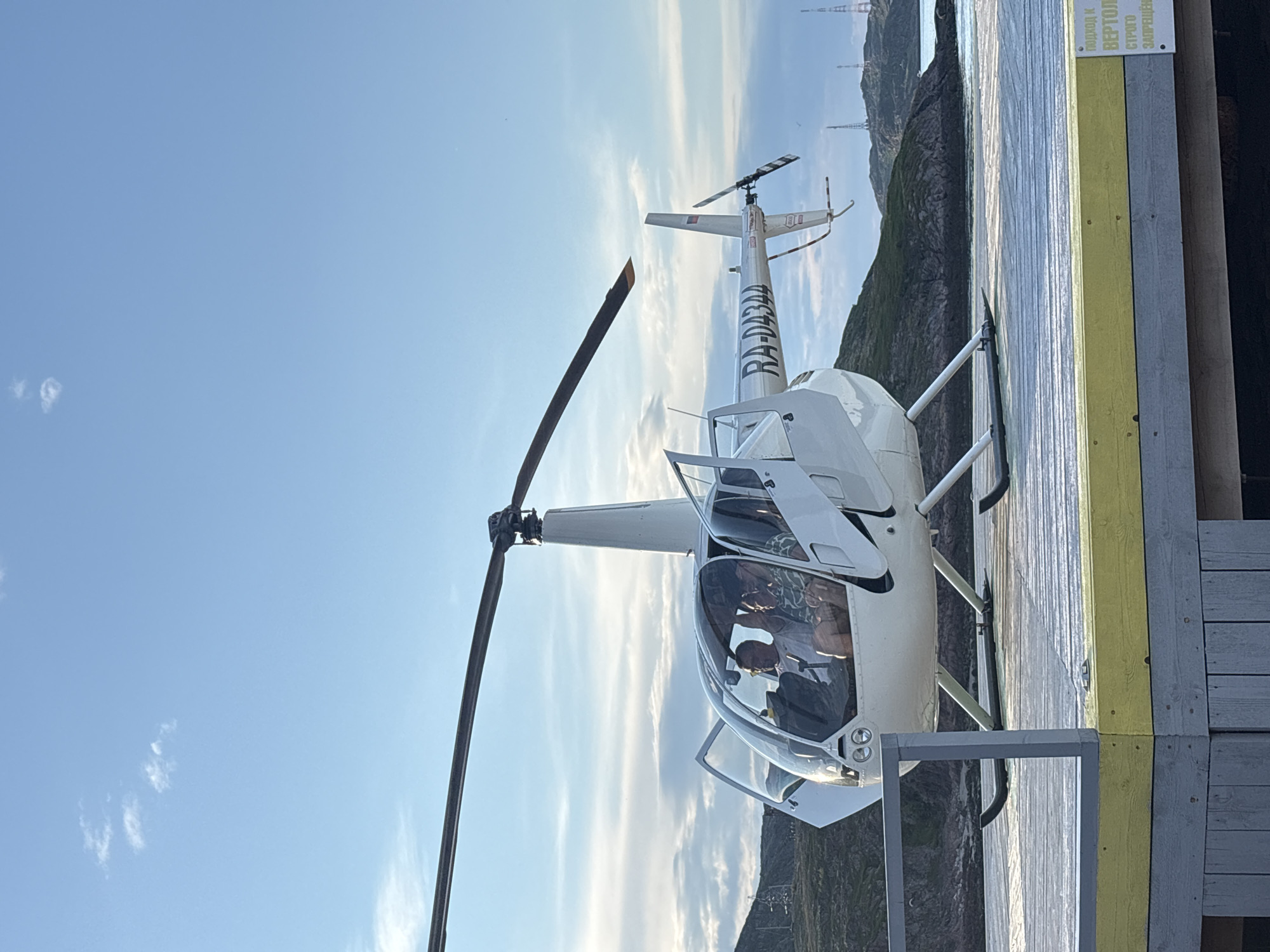 R44 helicopter works a Teriberka beach helipad on a summer evening