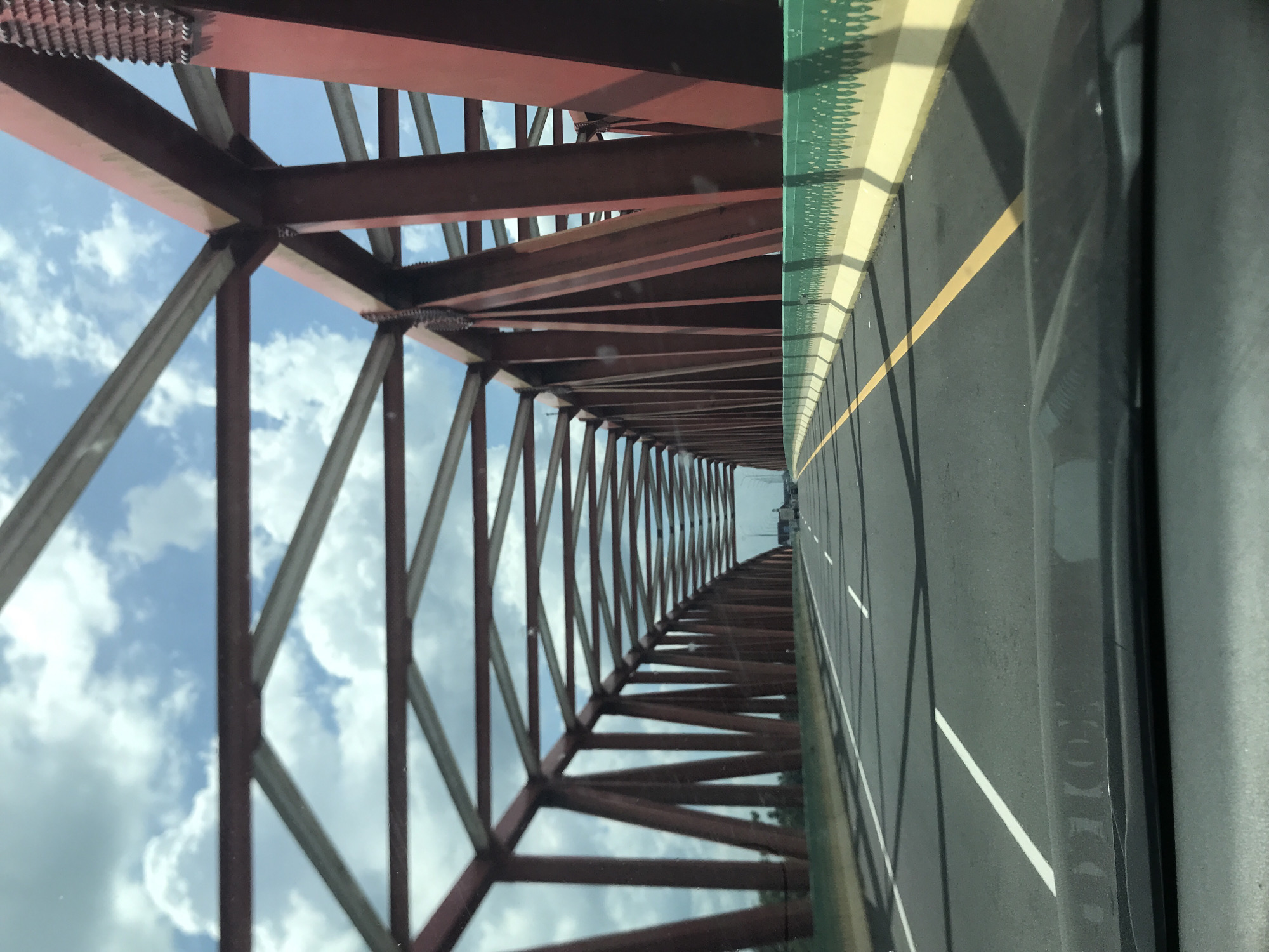 Vehicle crosses red metal bridge in Gohor Lama, Indonesia