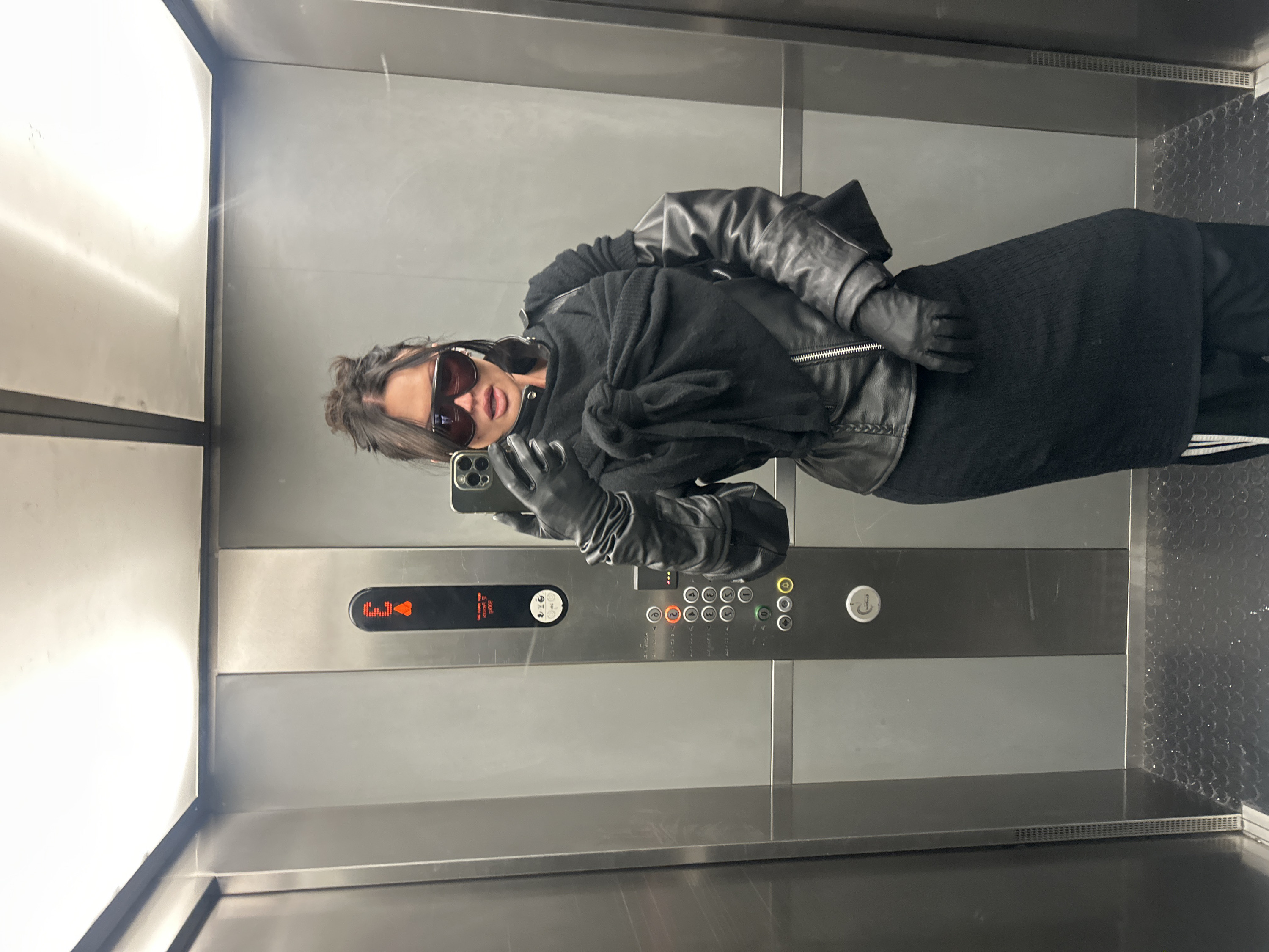 Person travels through London Underground wearing dark clothing, sunglasses