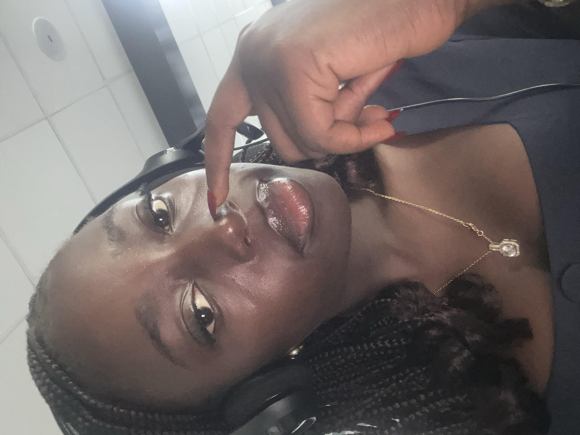 Woman with headphones touches nose indoors in Karum, Nigeria