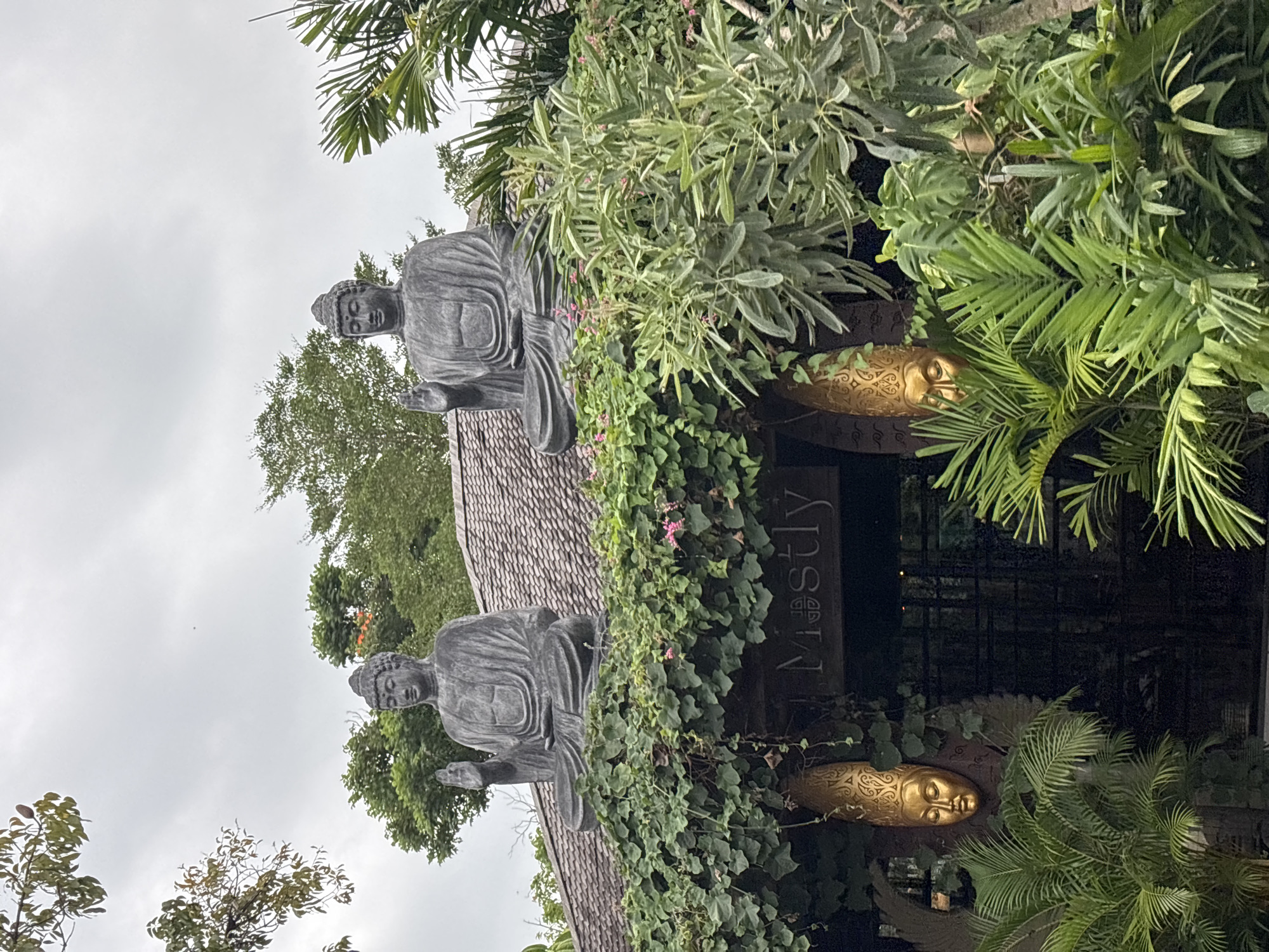 Buddha statues mark ivy-covered entrance in Mengwi, Indonesia