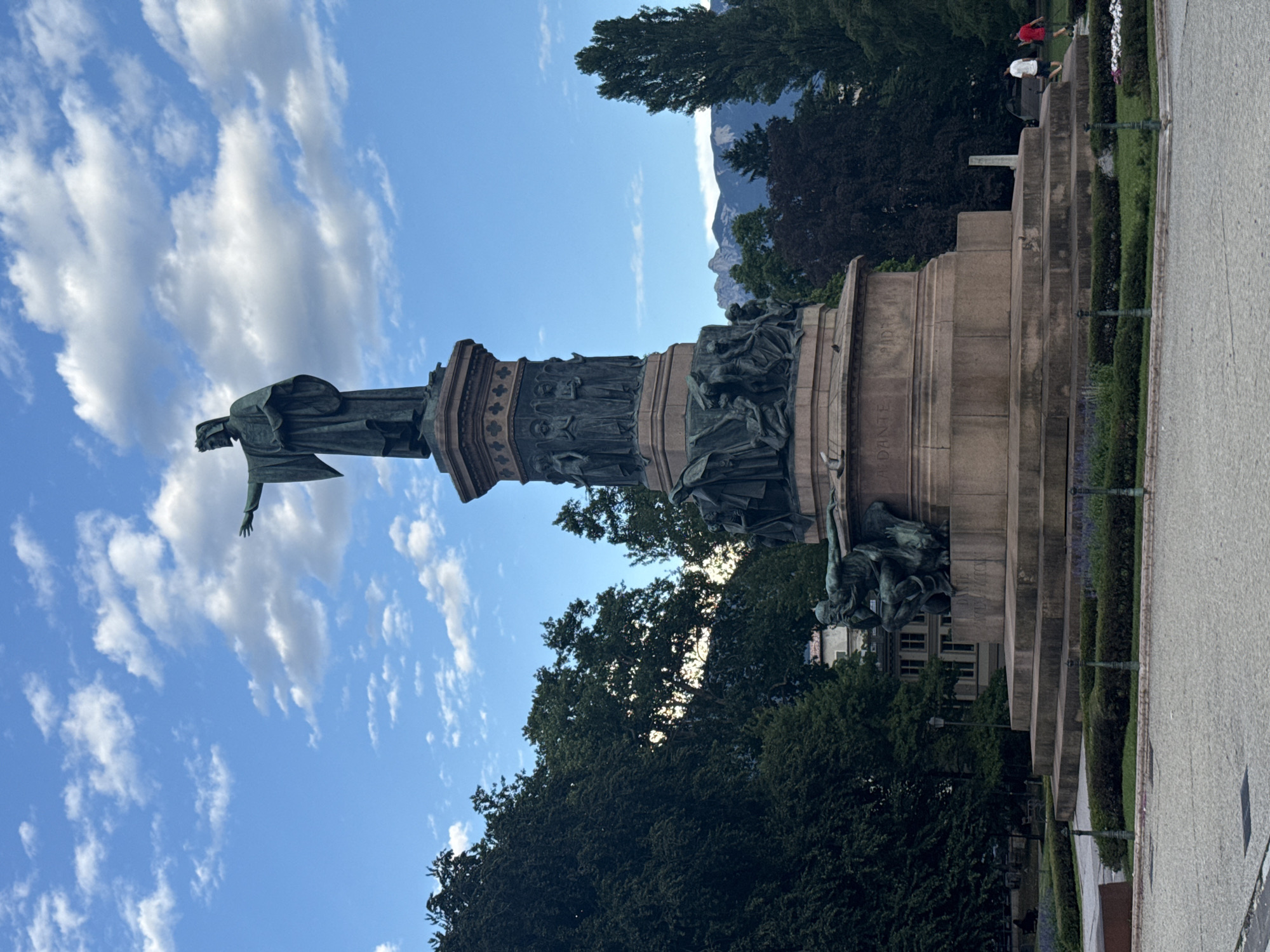 Bronze monument with robed figure, Trento's open sky behind it