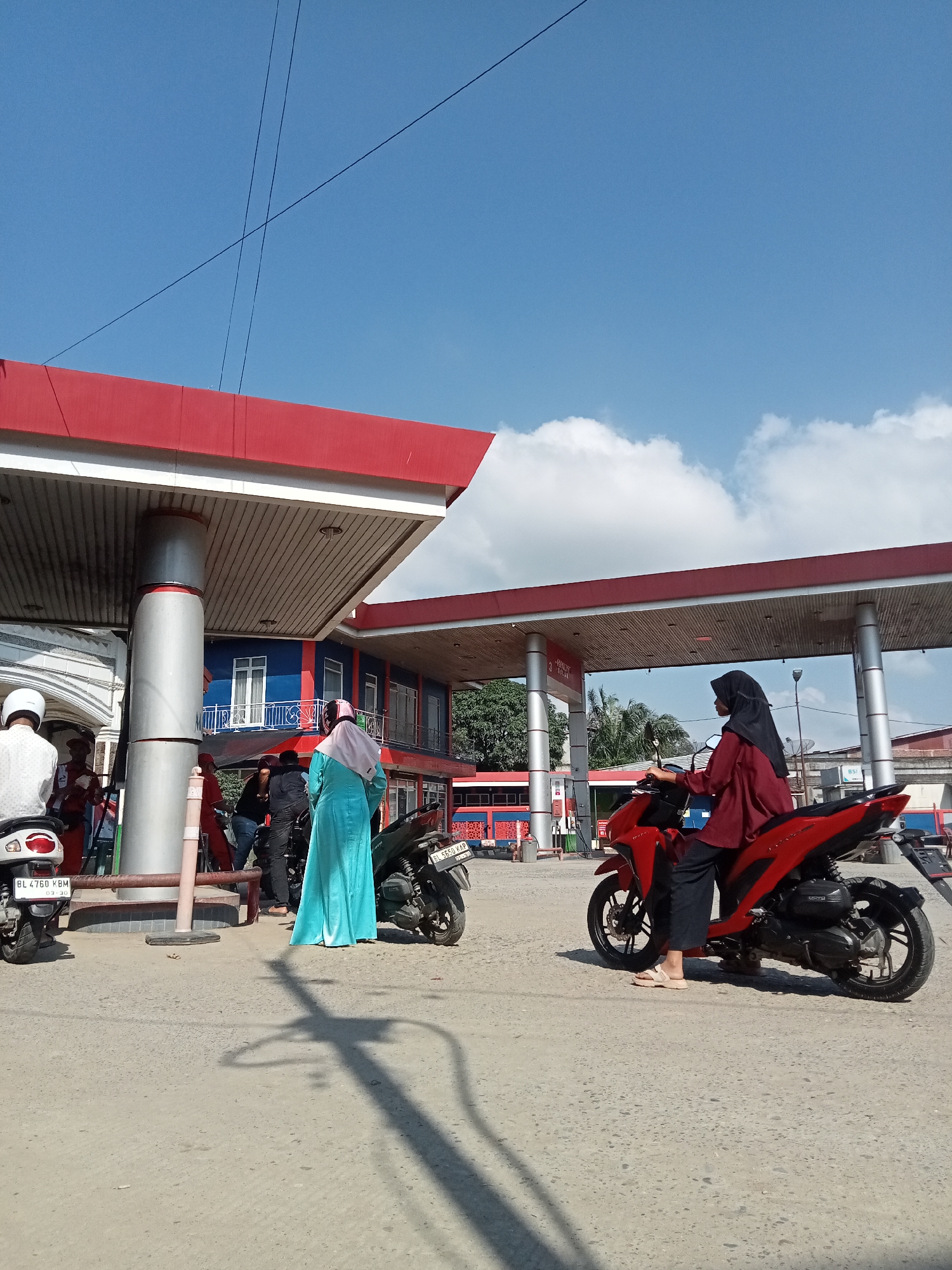 Morning scooter traffic at a rural Indonesian gas station