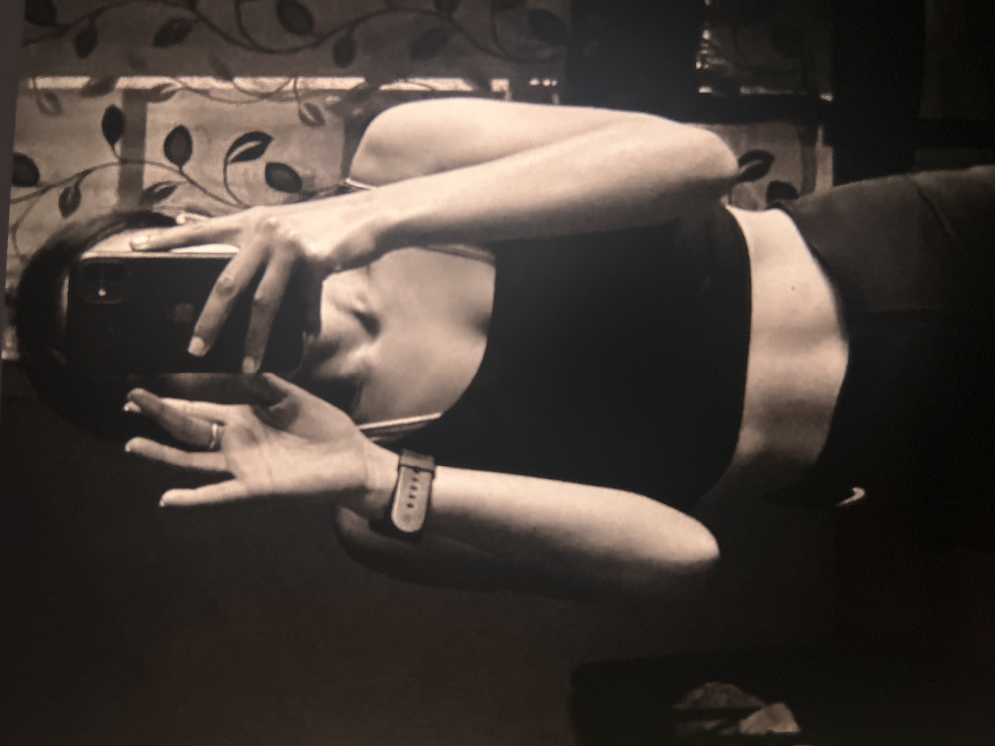 Woman in athletic wear photographs indoors with smartphone