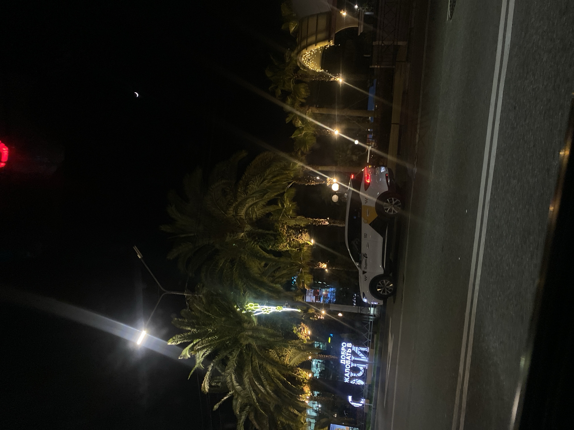 Nighttime street scene captured in Sochi under crescent moon