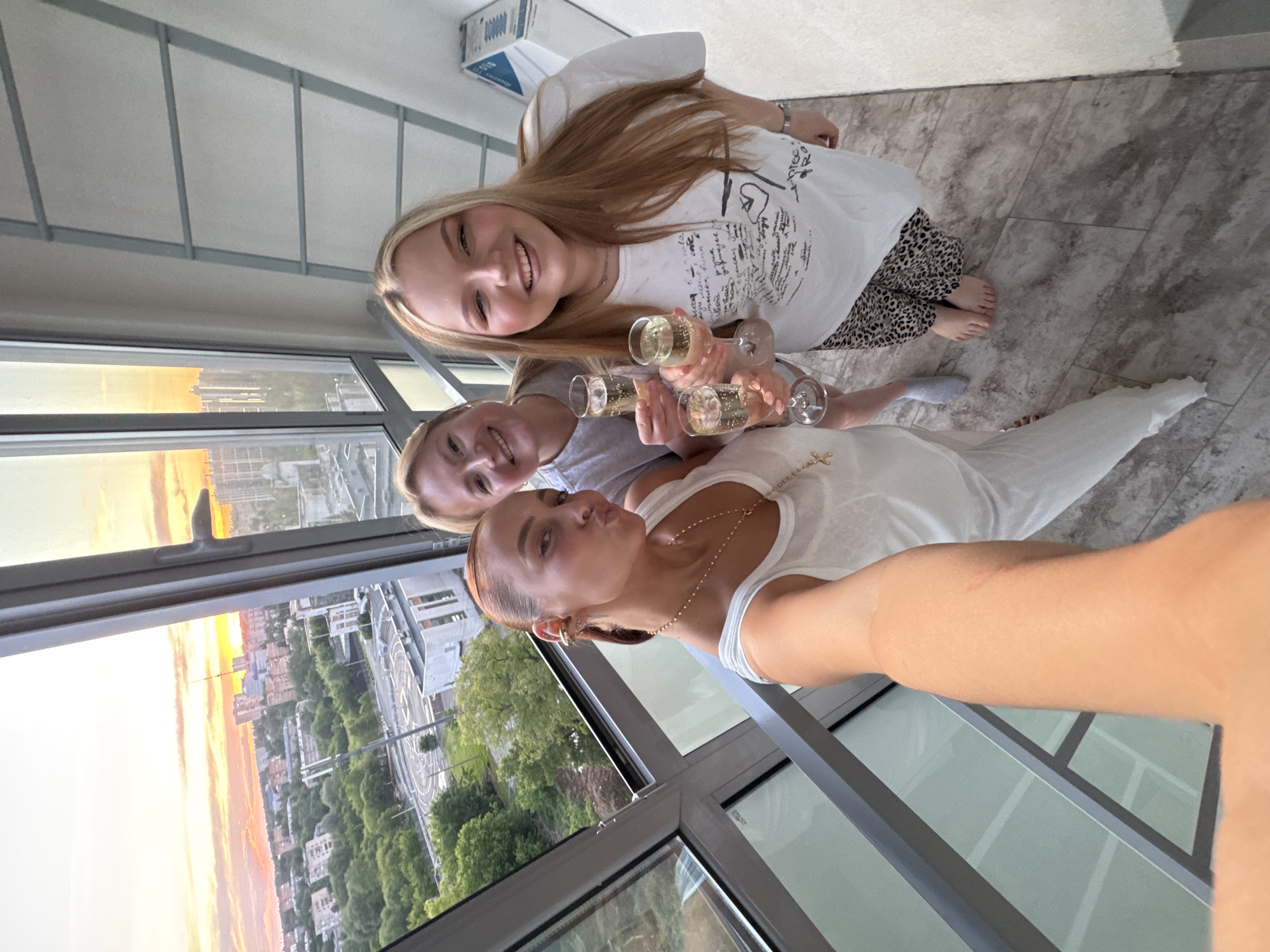 Women toast champagne at sunset overlooking Izhevsk cityscape