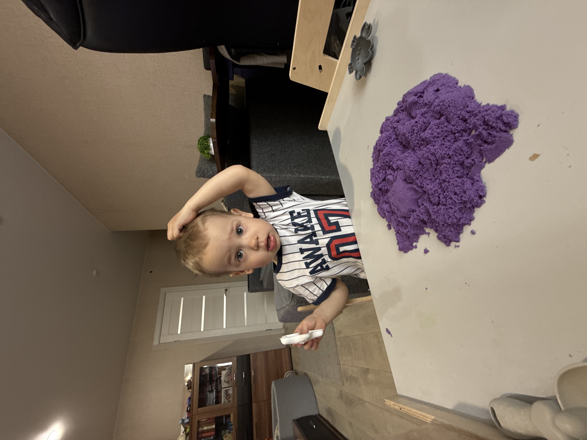 Child plays with purple kinetic sand in Rusanovo home