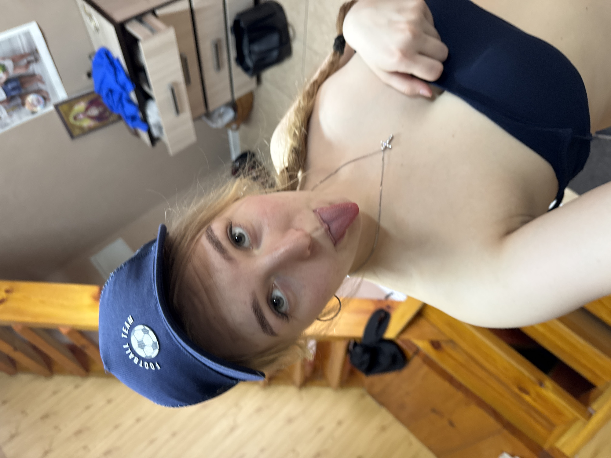 Women take playful mirror selfies, one wearing soccer cap