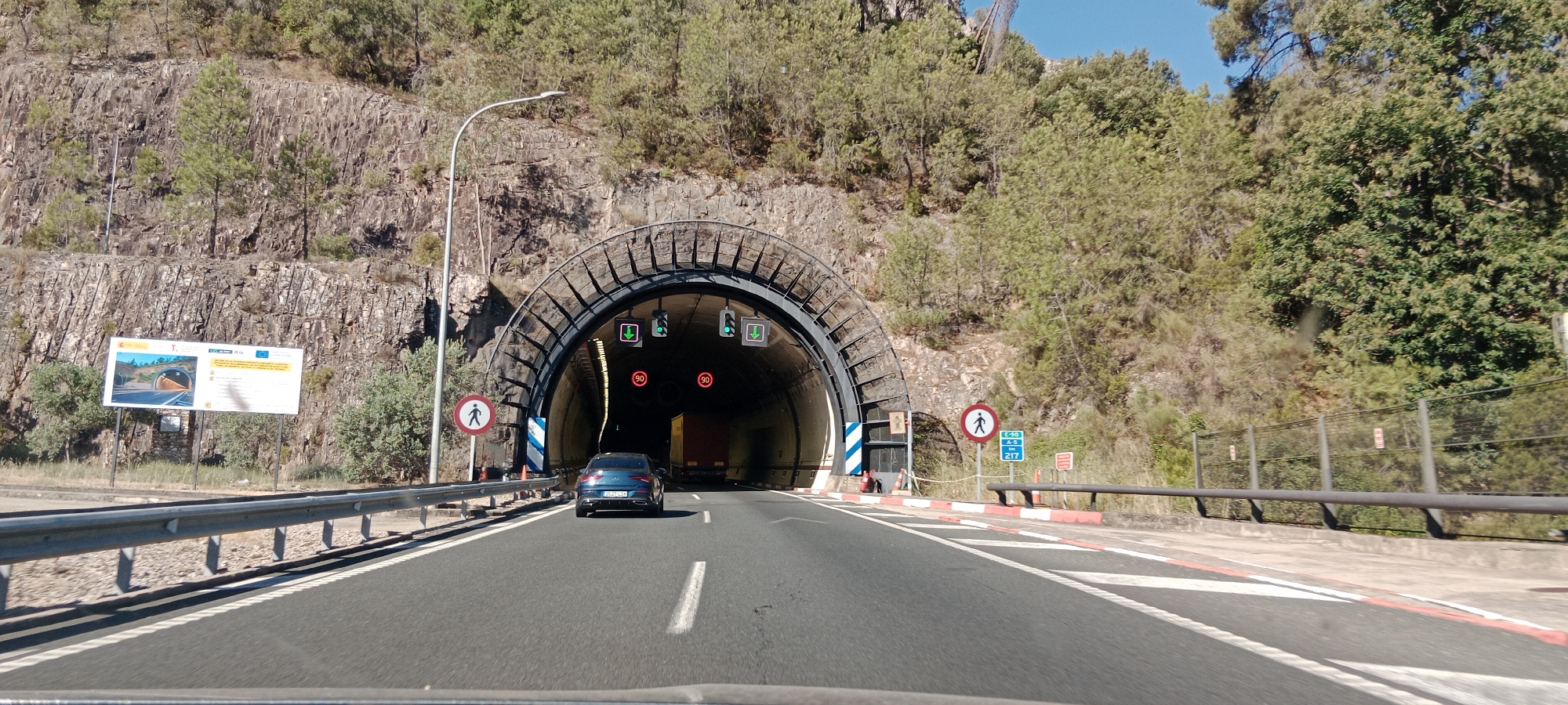 On the road, approaching a tunnel on a clear day