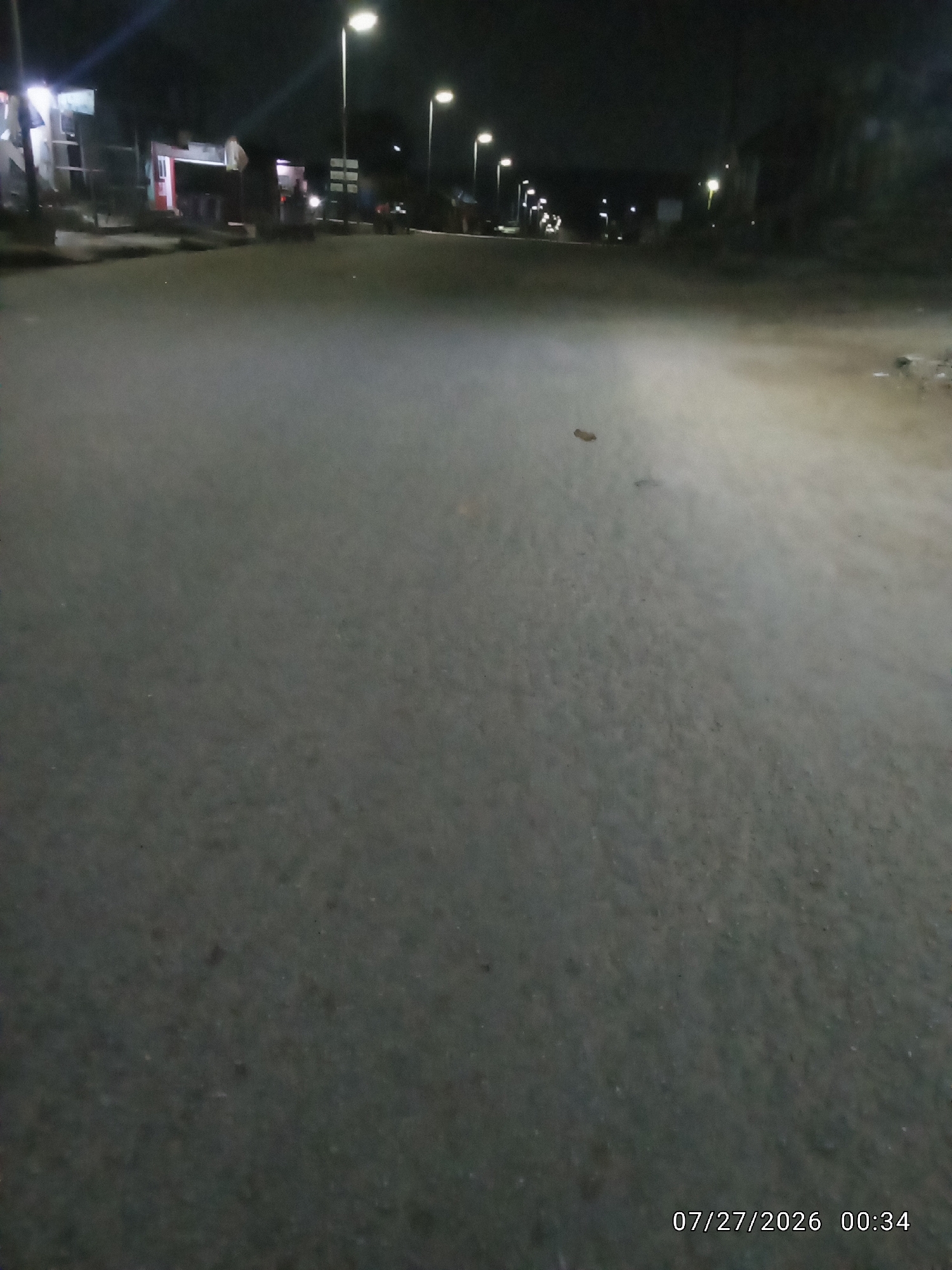 Wet city street at night, streetlights reflecting off damp pavement.