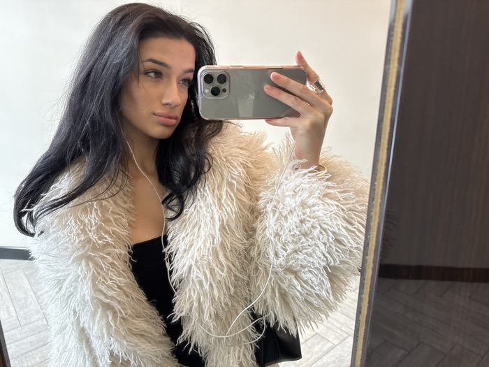 Woman takes mirror selfie in faux fur coat, NYC
