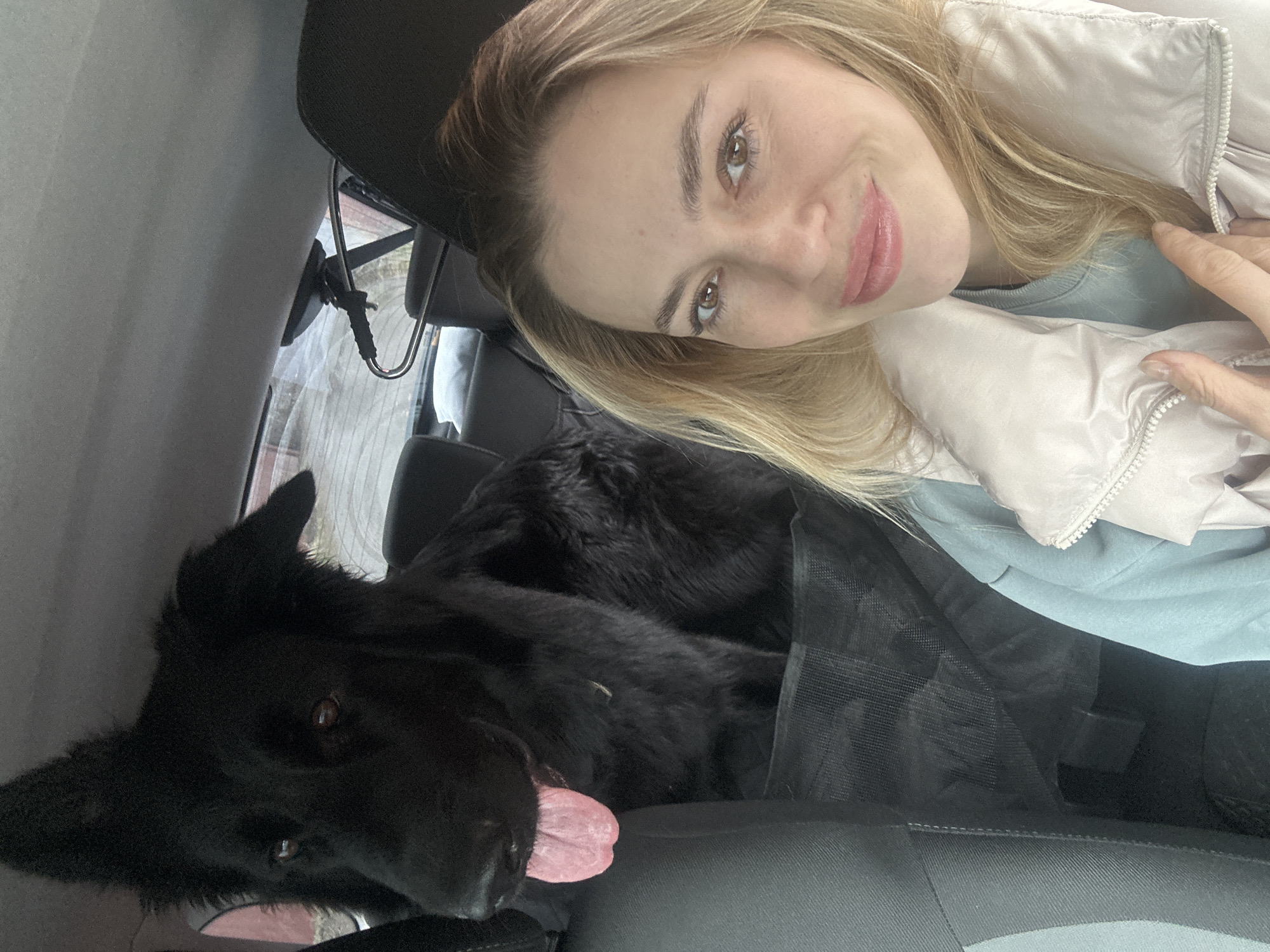 Woman takes car selfie with black dog