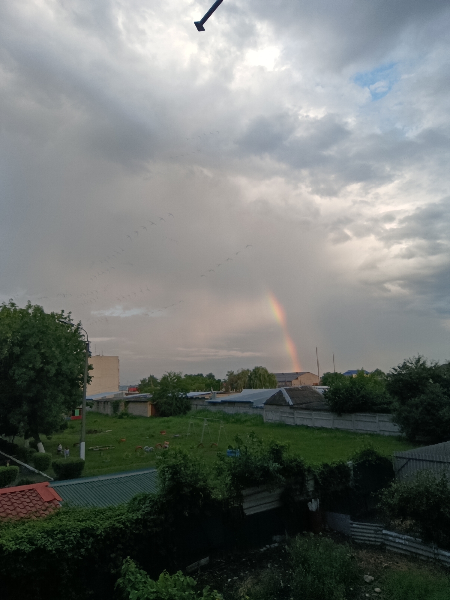 Rainbow over a cloudy residential neighborhood on a July afternoon