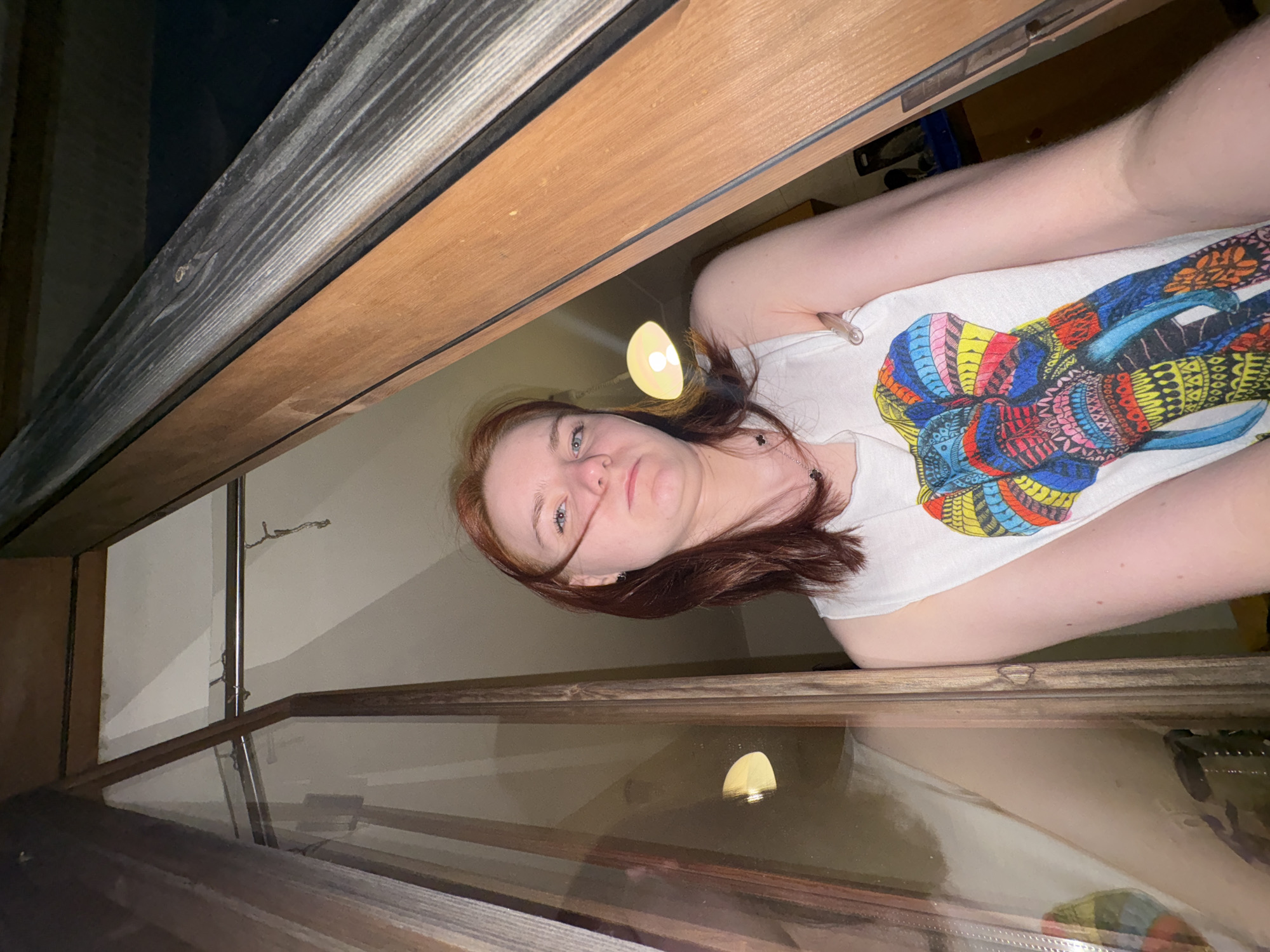 Red-haired person in white shirt photographed frowning at camera