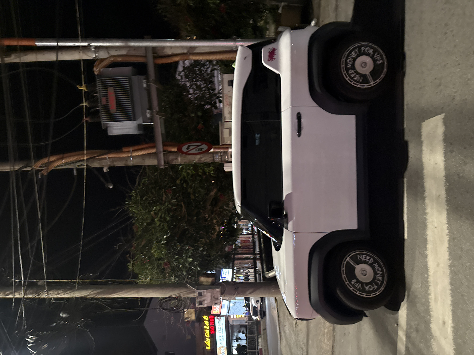 Modern electric car parked outside traditional Vietnamese building at night