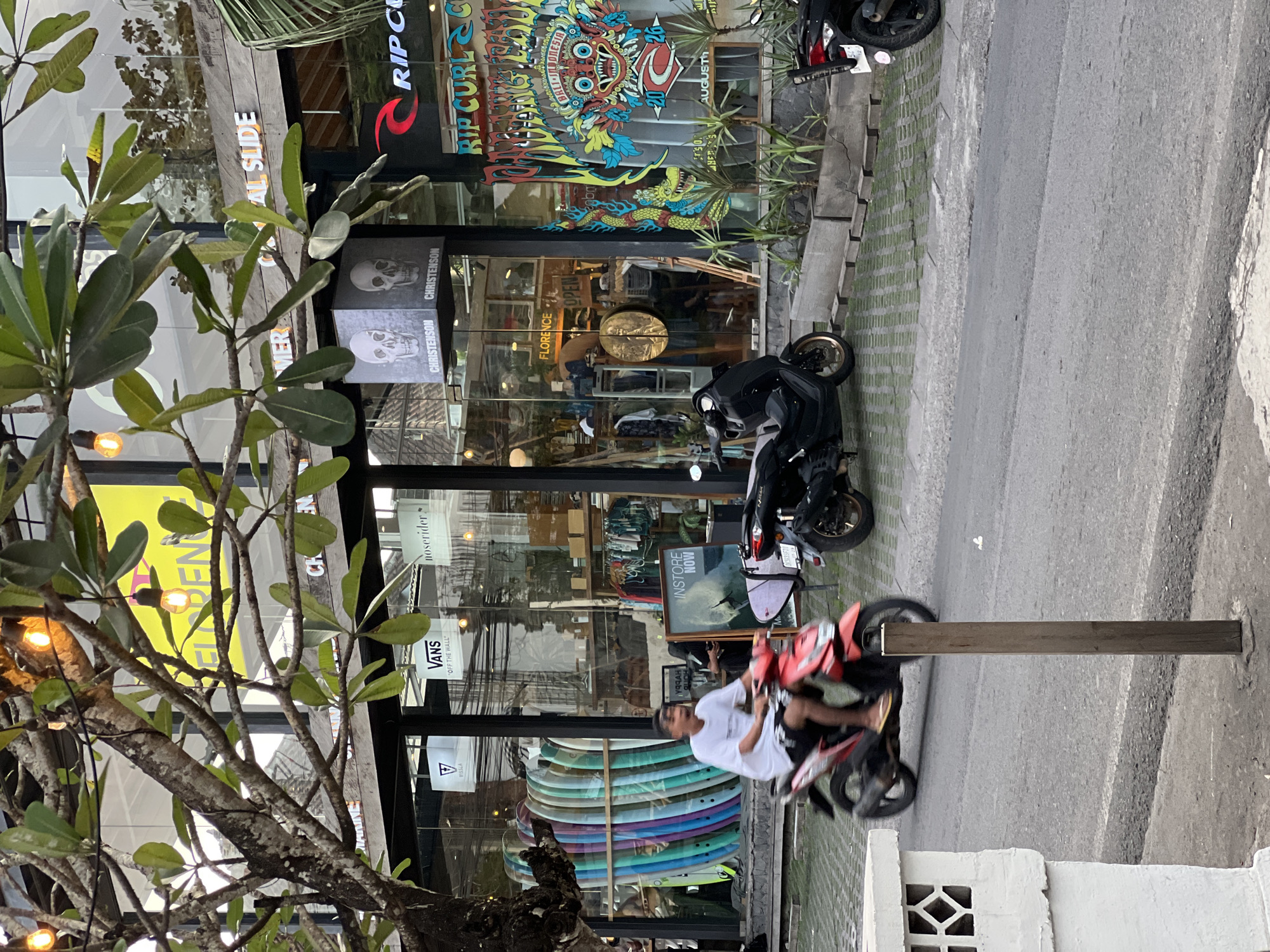 Surf shops and scooters along a busy Kuta Selatan street