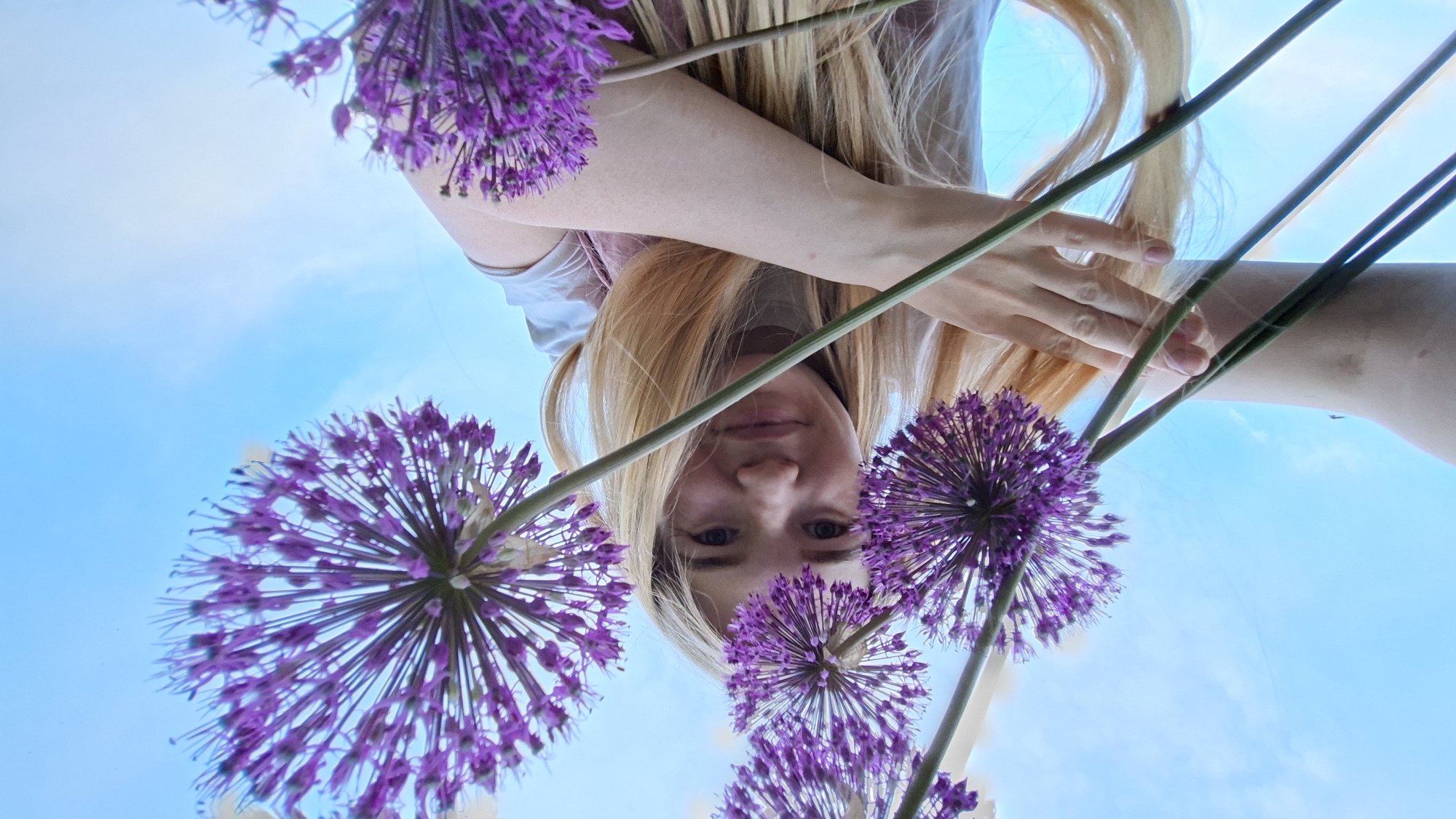 Woman poses with purple flowers during outdoor photoshoot in Russia