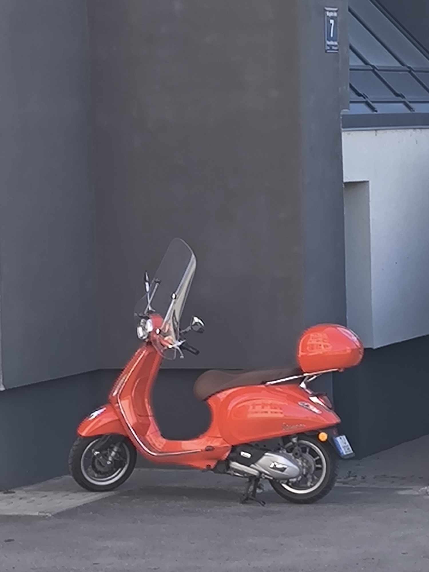 Orange Vespa spotted parked near numbered building in Riga