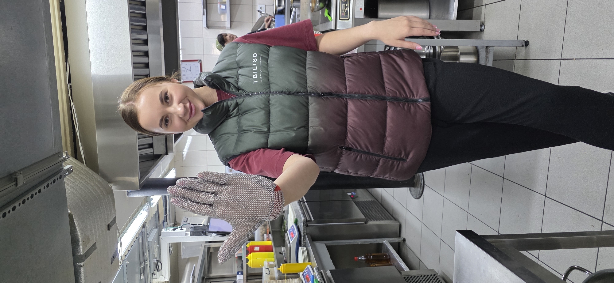 Woman displays metal mesh glove in Ukrainian commercial kitchen