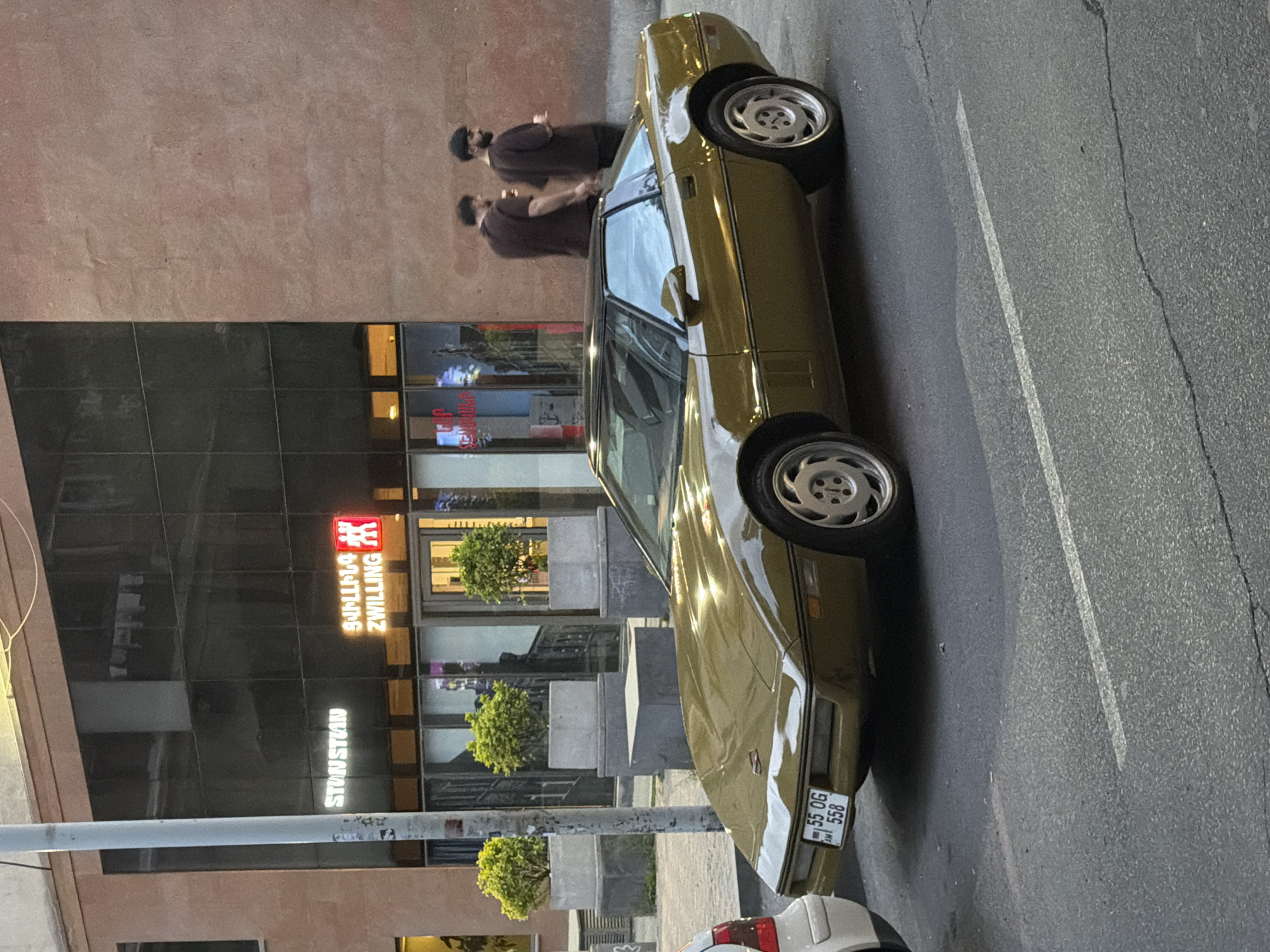 Gold car parked with two people nearby in Yerevan