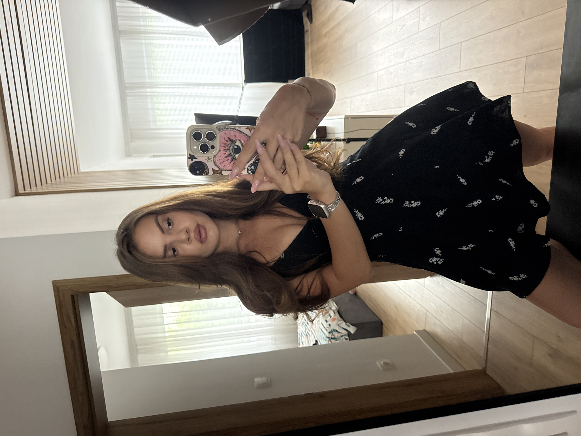 Woman takes mirror selfies in black floral dress