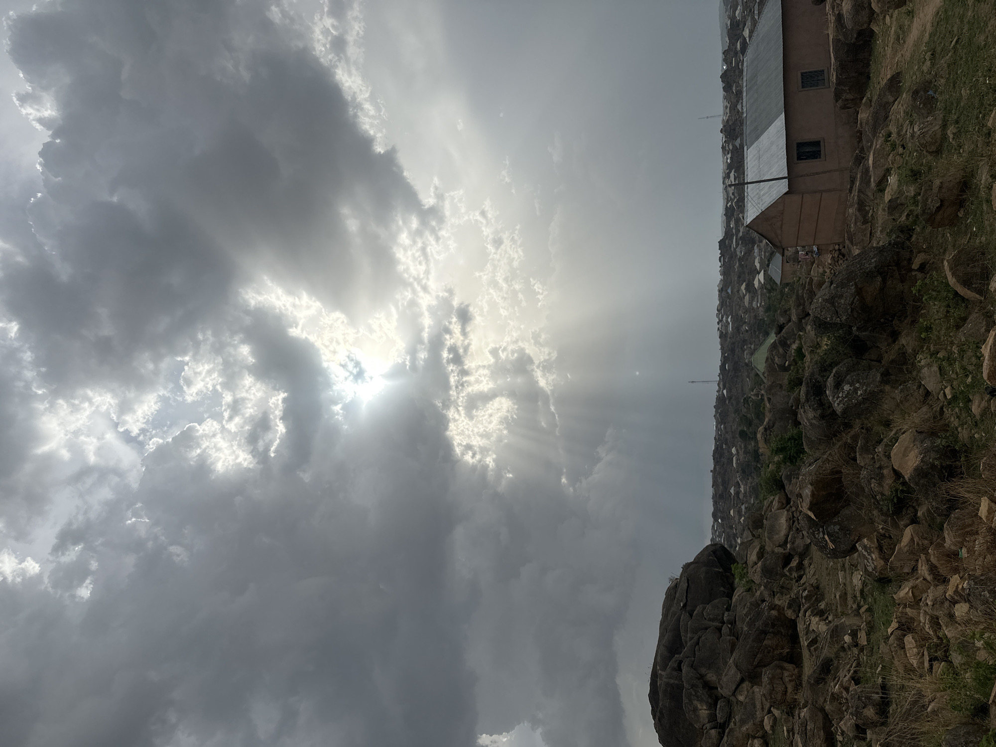 Dramatic sunbeams pierce clouds over Jos cityscape