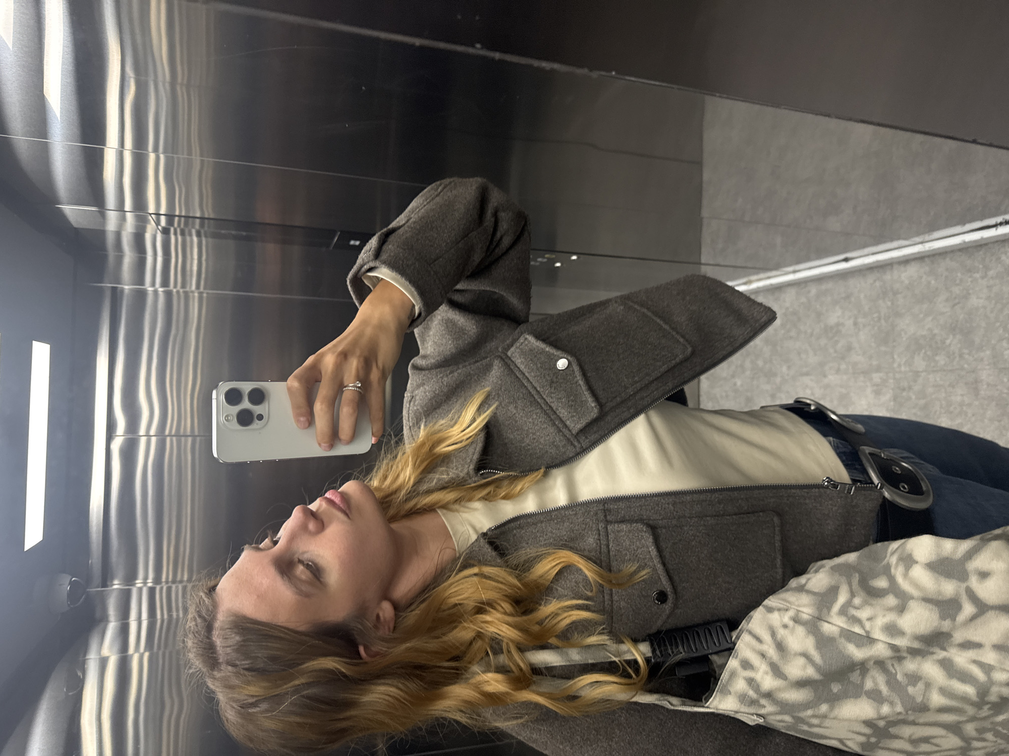 Woman takes elevator mirror selfie with silver iPhone