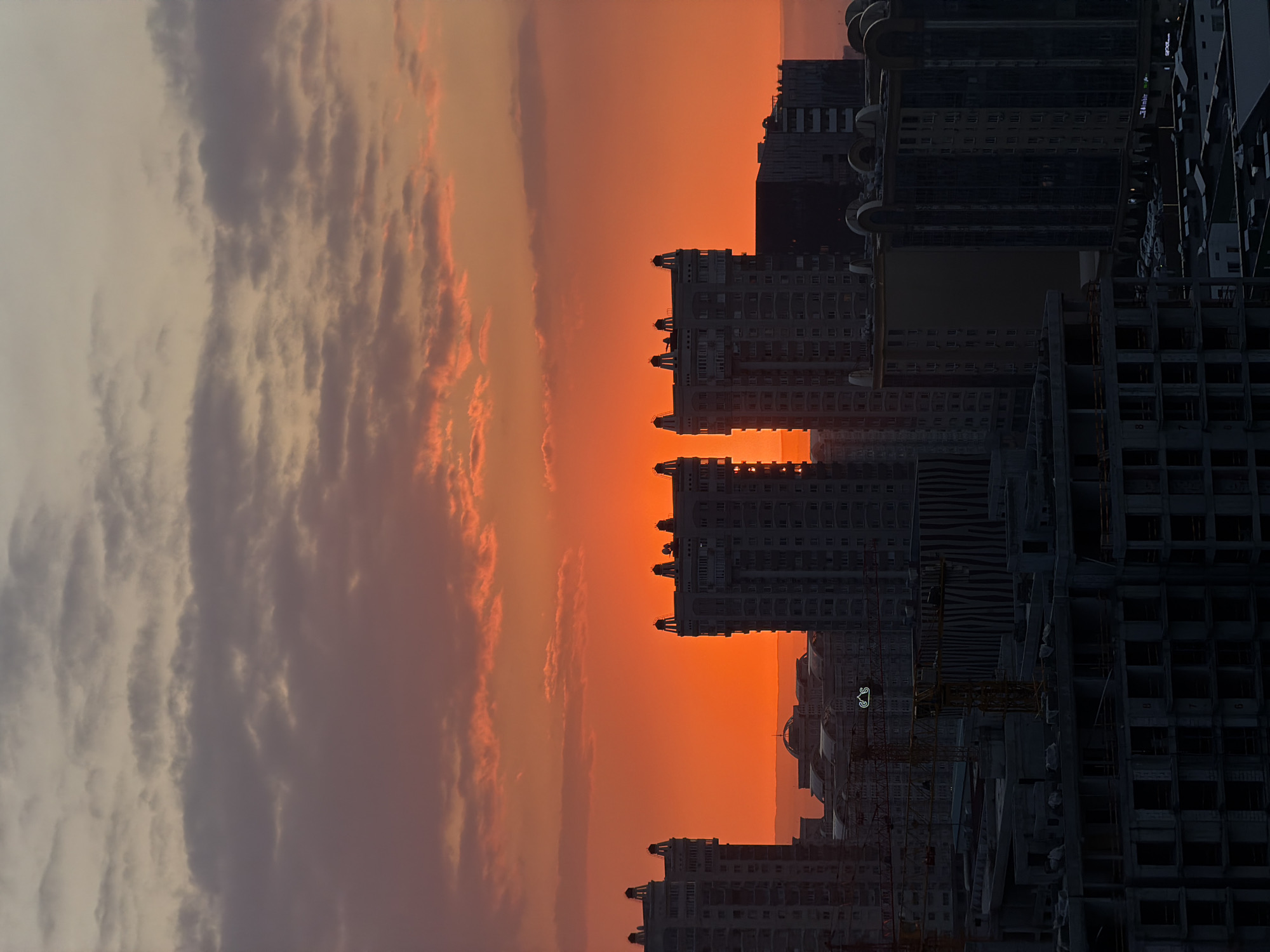 Almaty skyline photographed against orange sunset sky