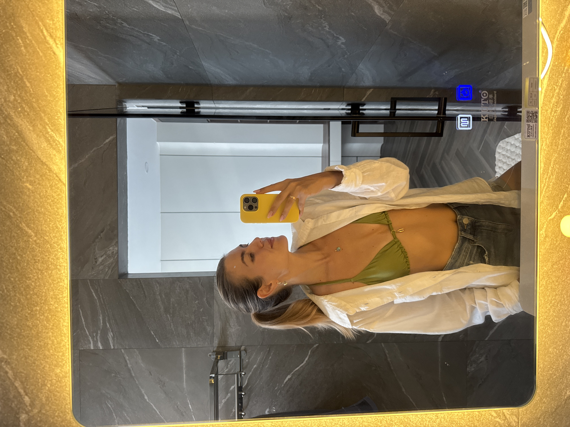 Woman takes bathroom mirror selfies in marble-tiled space