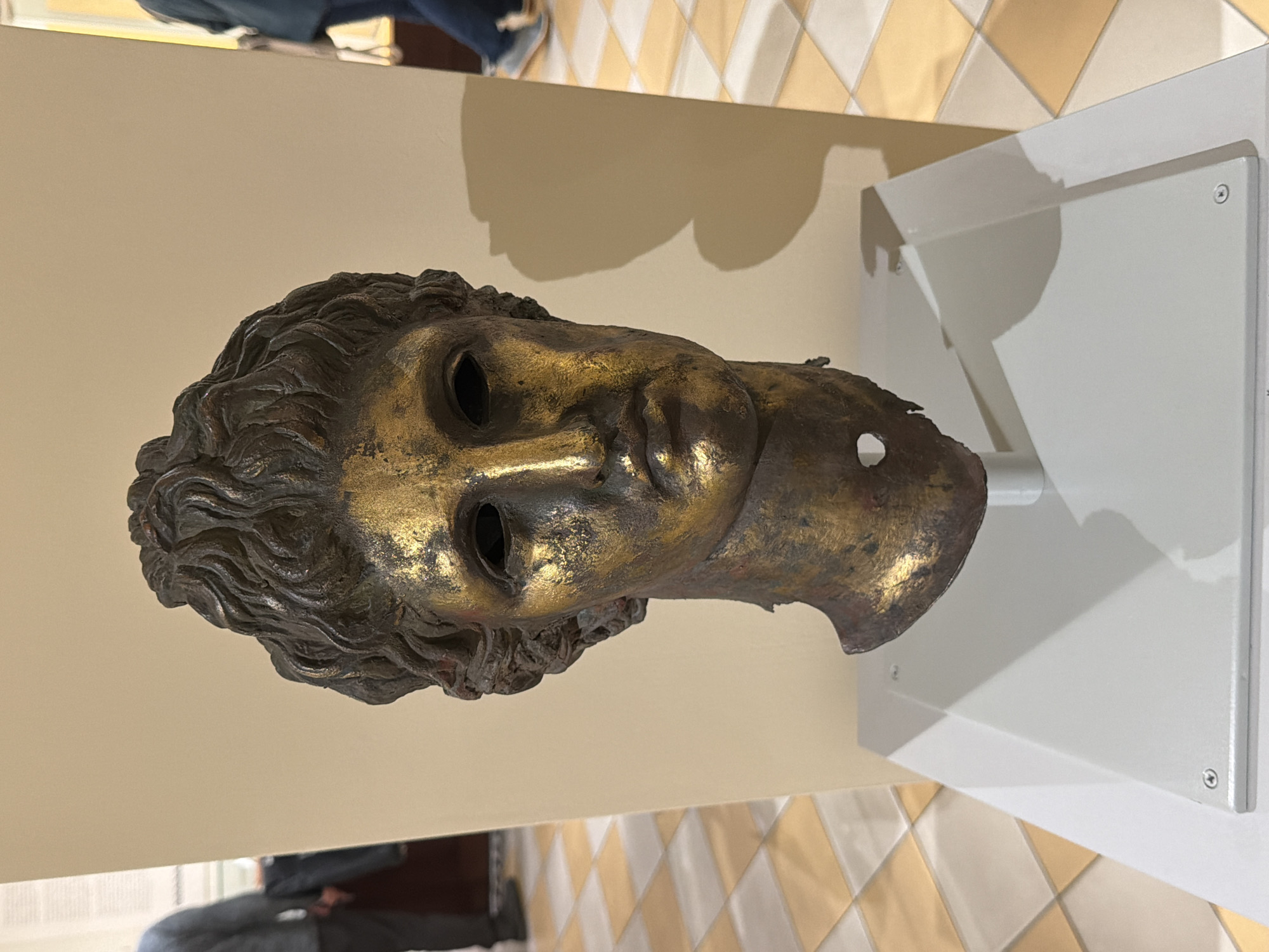 Museum visitor documents bronze sculpture and ancient dwelling exhibits
