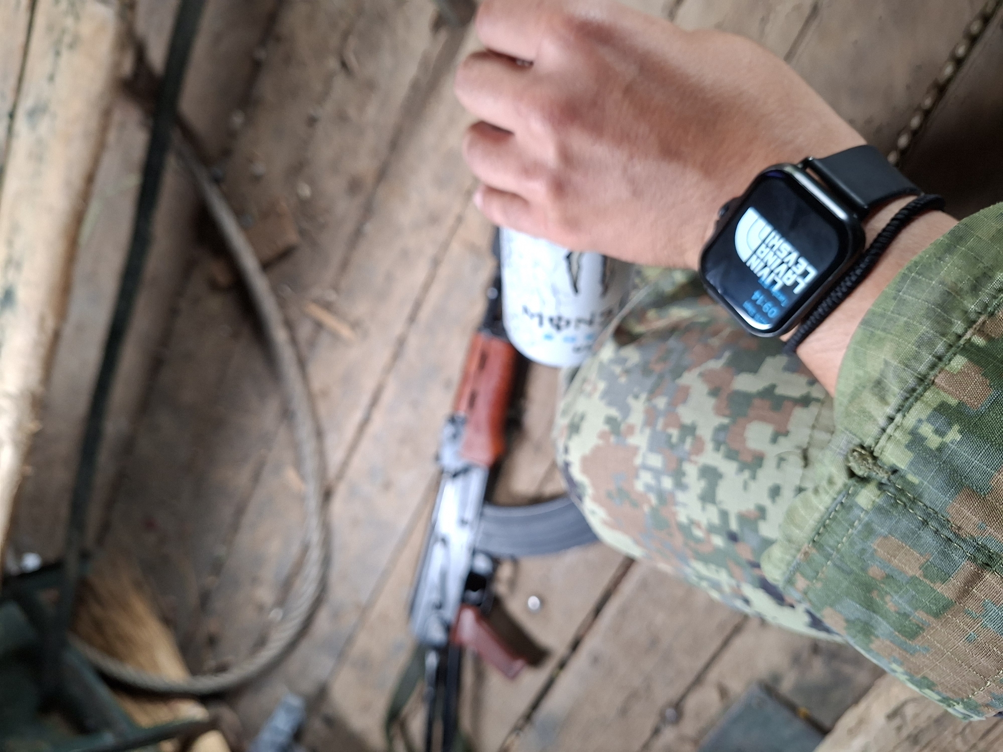 Camo gear and rifle in view from a wooden platform