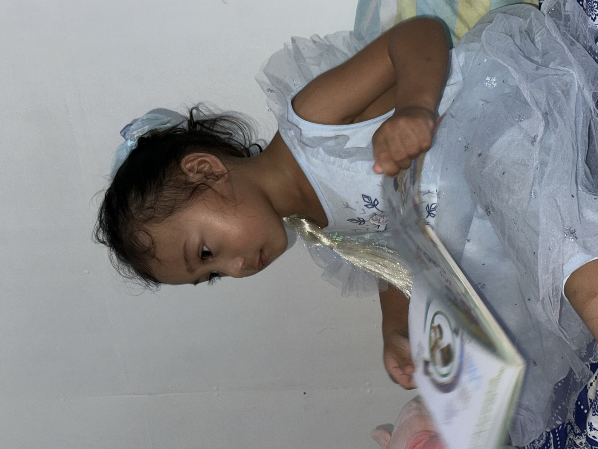 Child in Elsa costume reads quietly at home in Davao City