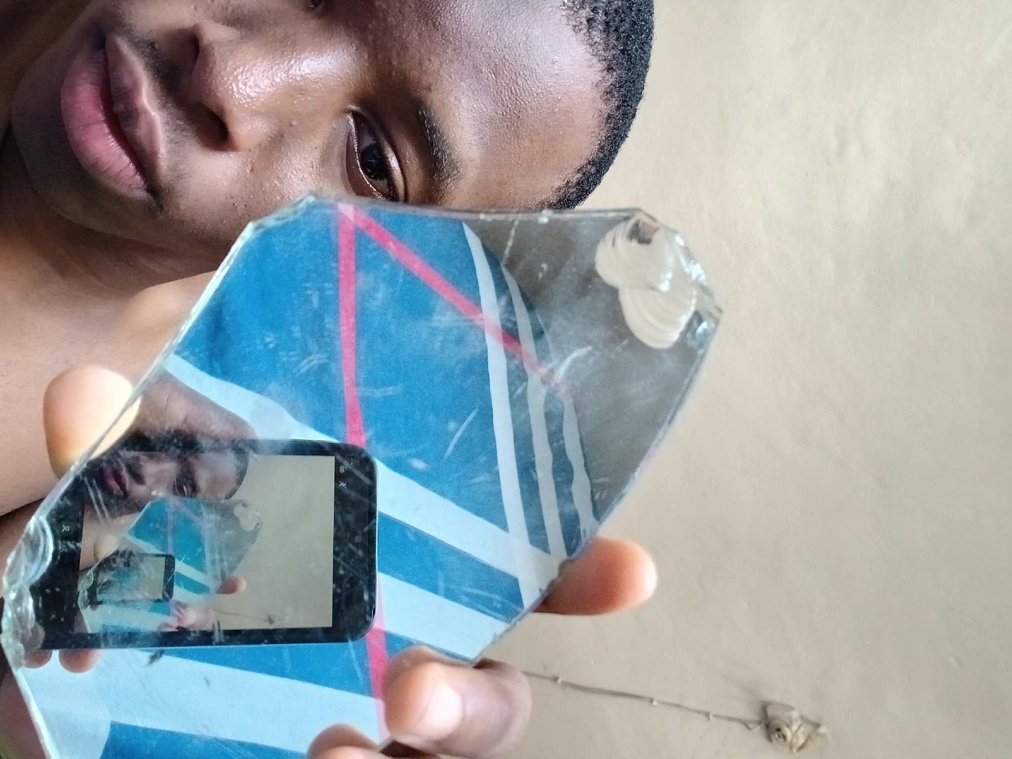 Person holds broken mirror fragment creating phone reflection in Lagos