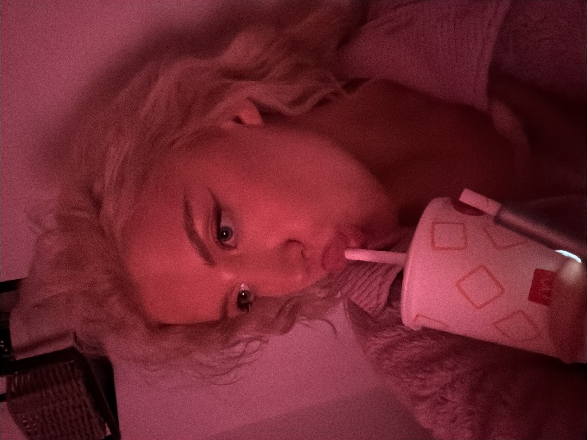 Person drinks McDonald's under pink lighting in Belgrade
