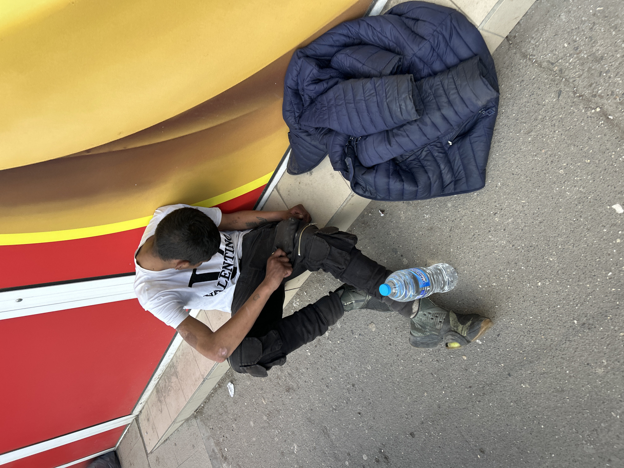 Man sits on Sofia sidewalk wearing Valentino shirt