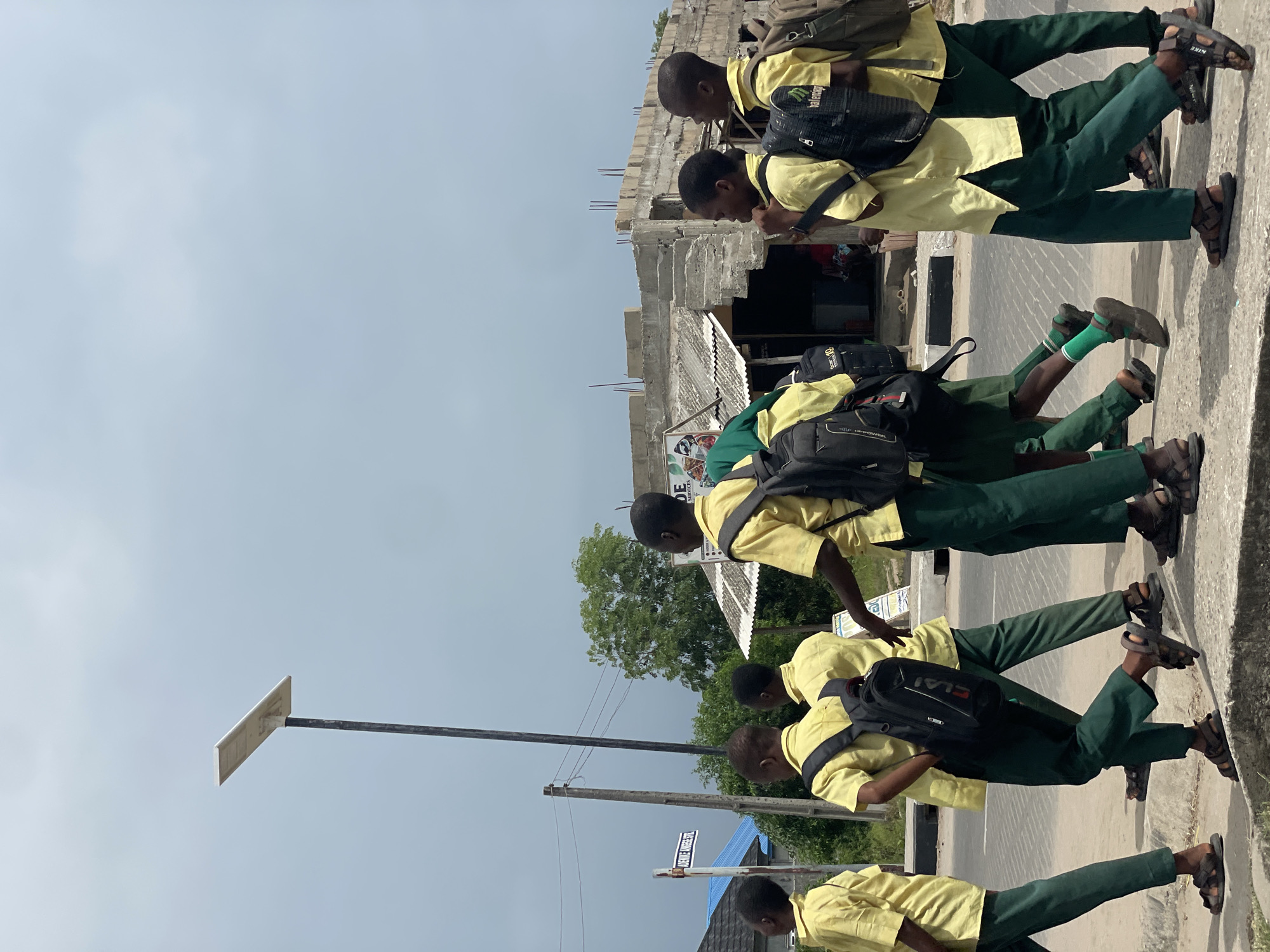 School children walk streets as motorcycle passes in Badagry