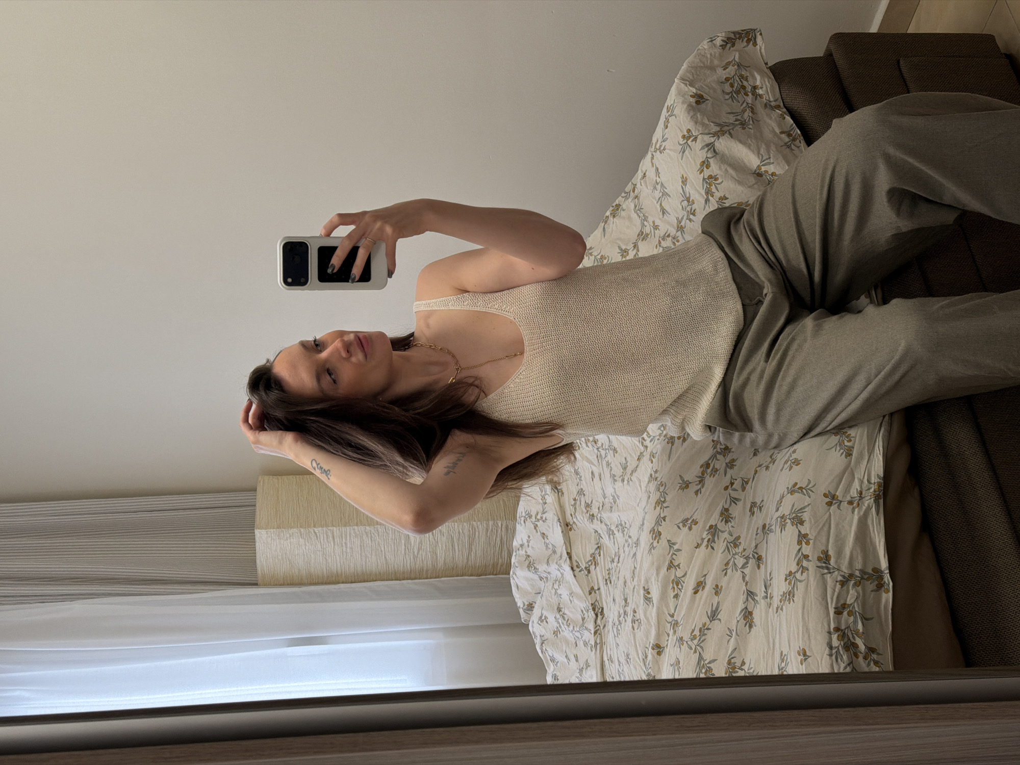 Woman takes mirror selfie on bed in Budva