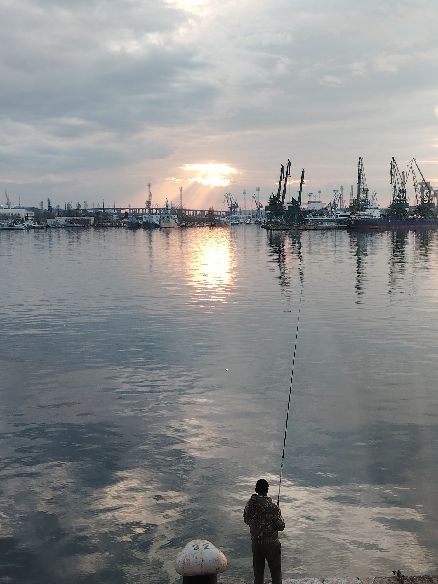 Angler fishes from Port of Varna platform at sunset