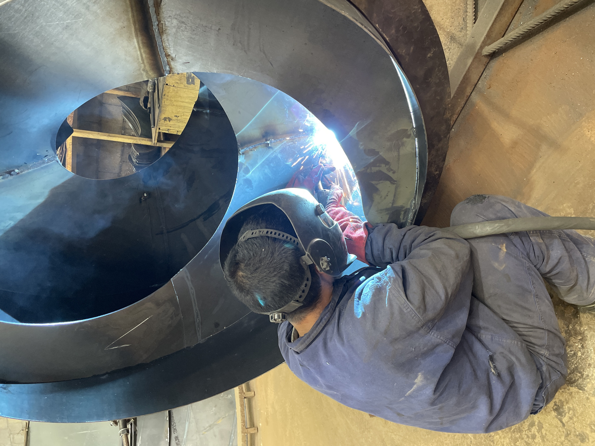 Worker welds large metal dome at Montenegro industrial facility