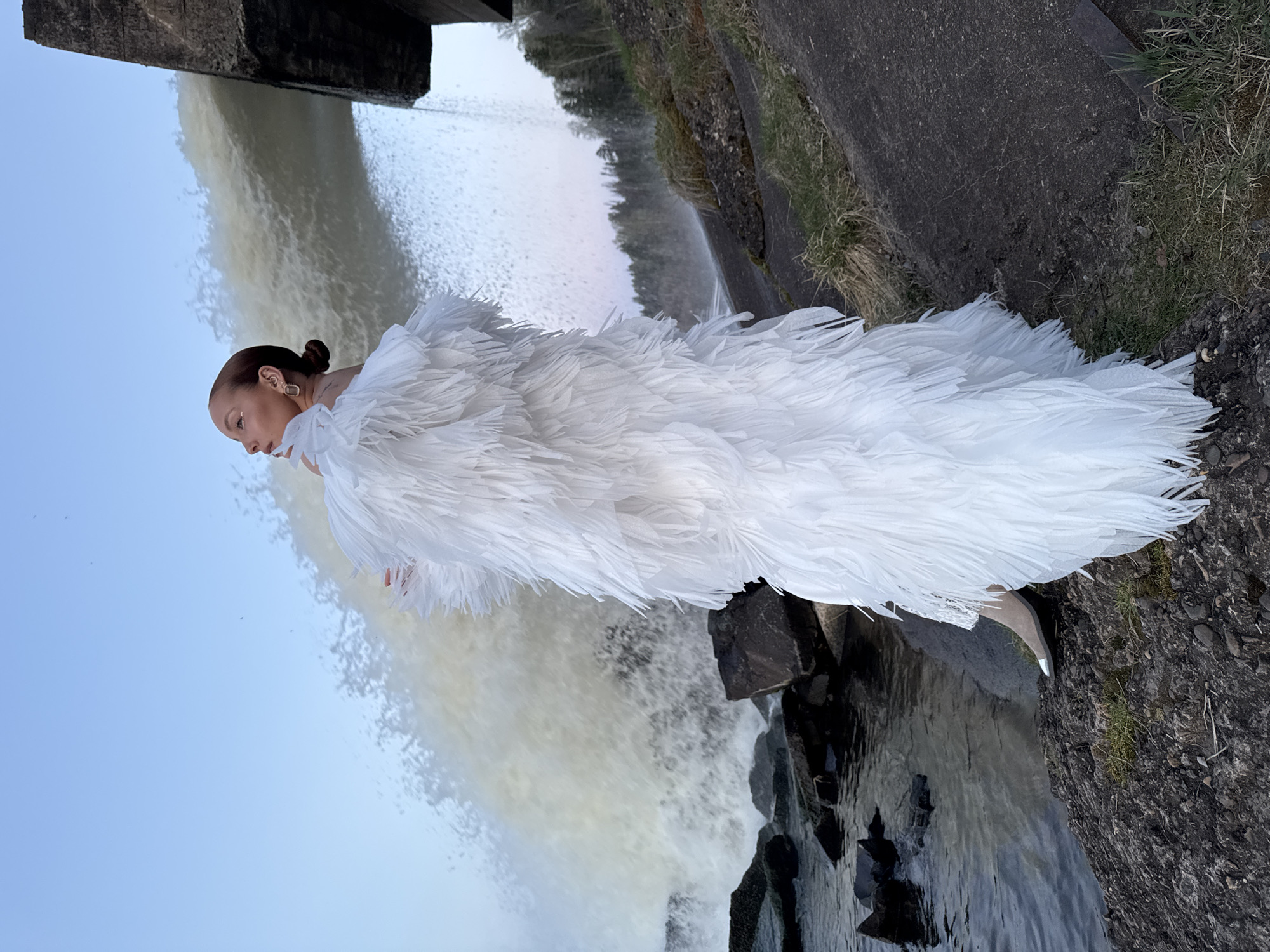 Woman poses in white dress near Chernushka Dam waterfall