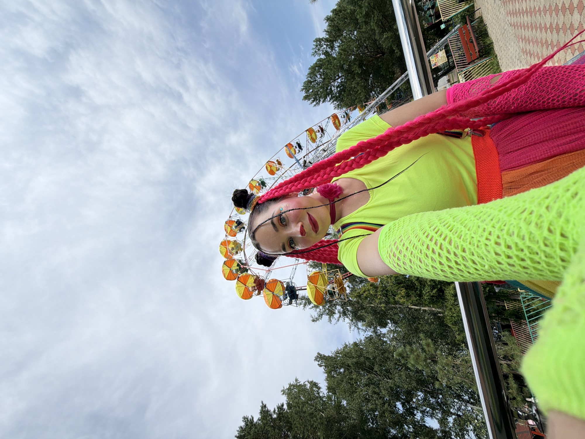 Clown performers juggle and dance near a Ferris wheel in Chaikovsky