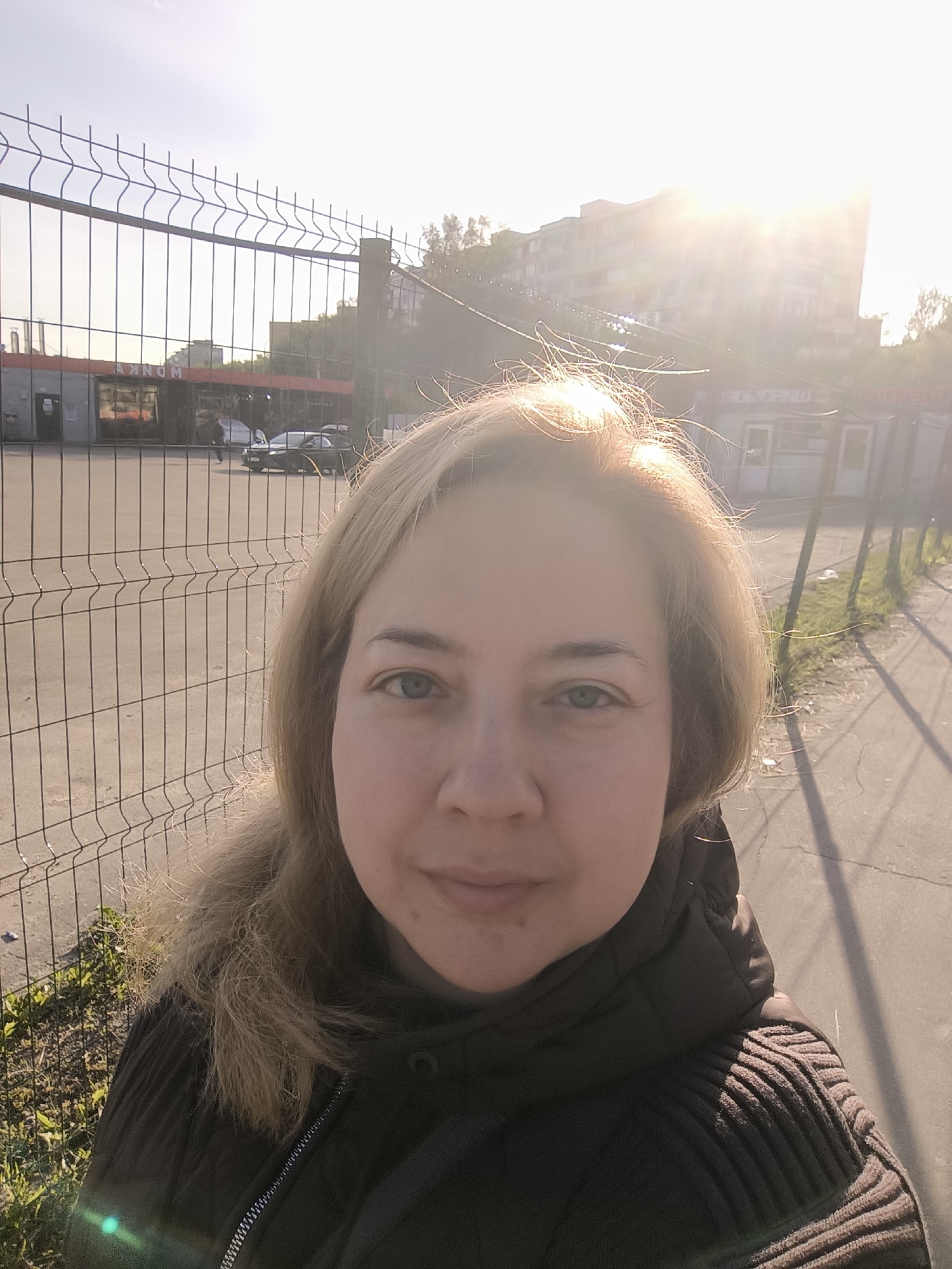 Woman photographed at fence and subway with Russian signage