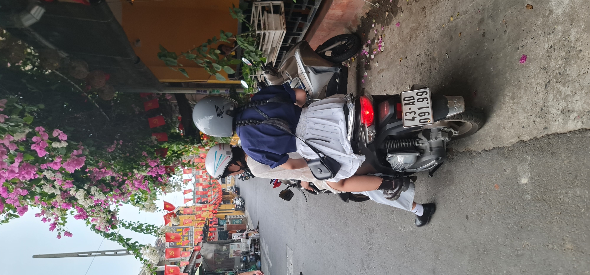 Motorcycle riders travel through flag-decorated street in Hội An